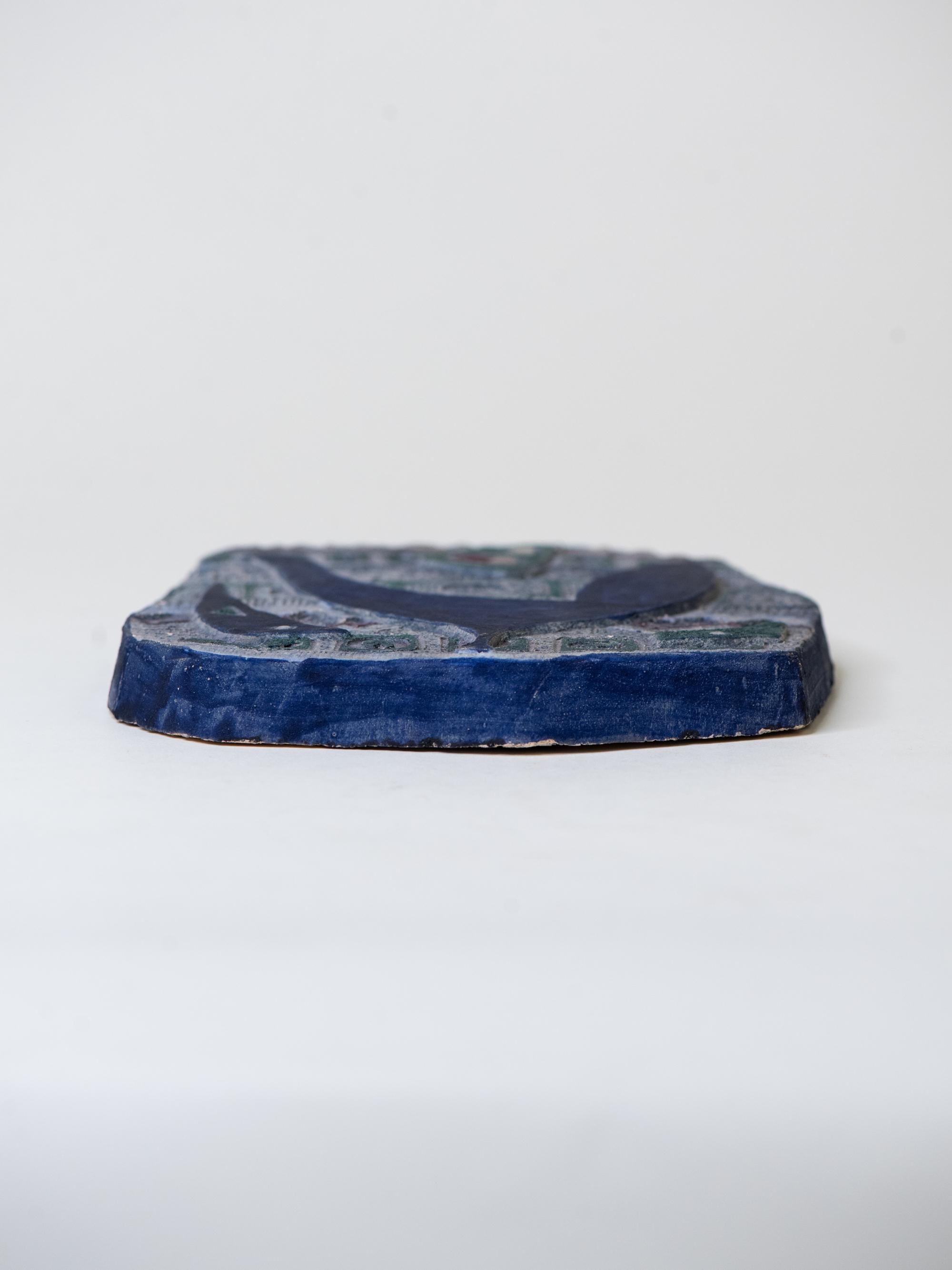 Un relief mural en céramique rare et expressif de l'artiste suédoise Eva Hellbom. Cette pièce fabriquée à la main présente des formes abstraites audacieuses dans des tons riches de bleu profond, de vert forêt, de bordeaux et de prune, sur un fond