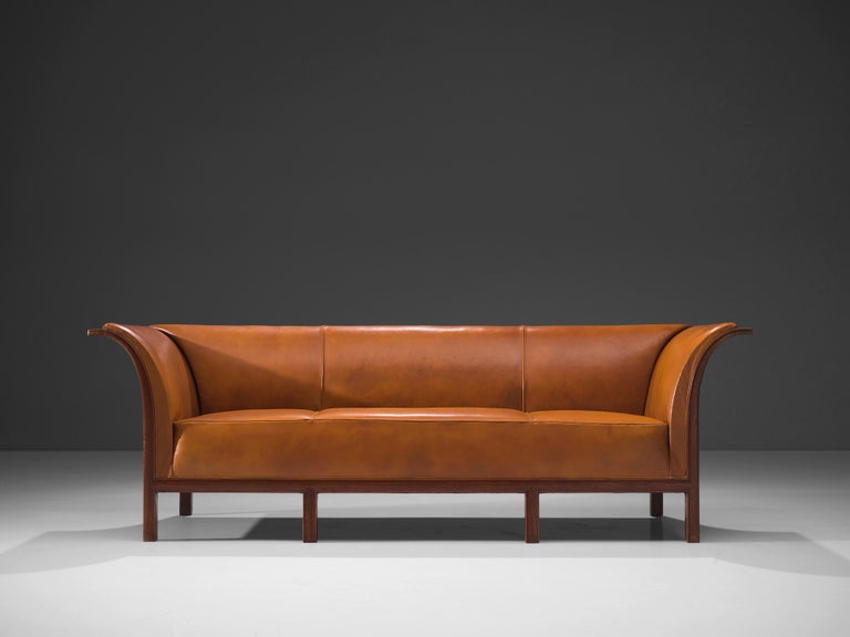 Frits Henningsen, sofa, teak, cognac leather, Denmark, 1930s

This classic sofa was designed and produced by master cabinetmaker Frits Henningsen in the 1930s. The design is well-balanced, showing an interesting contrast between the straight lines