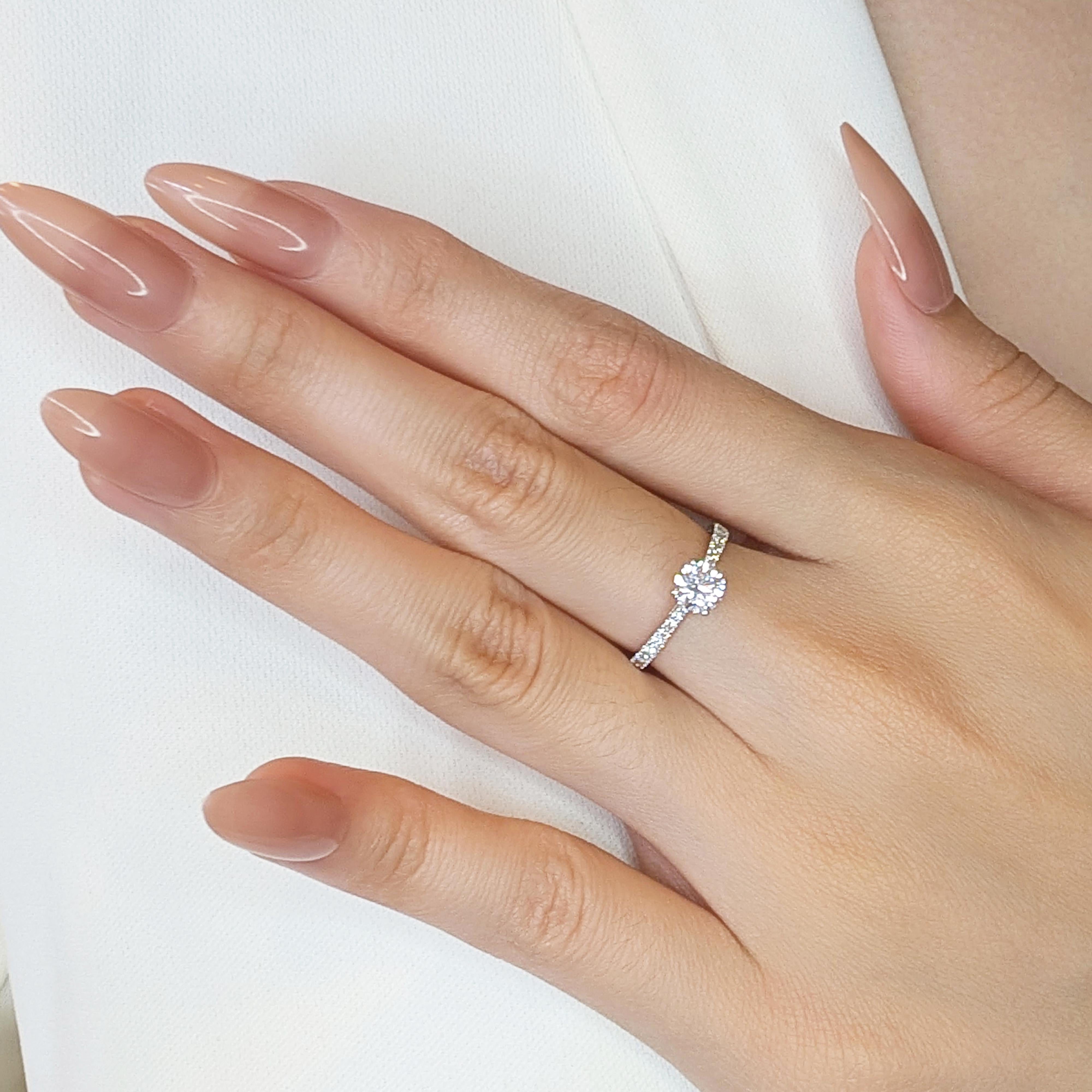 Questo eccezionale anello con pavé emana grazia e raffinatezza, realizzato in lussuoso oro bianco 18 carati per una finitura elegante e raffinata. Il cuore di questo gioiello è costituito da uno splendido diamante naturale da 0,63 carati con taglio