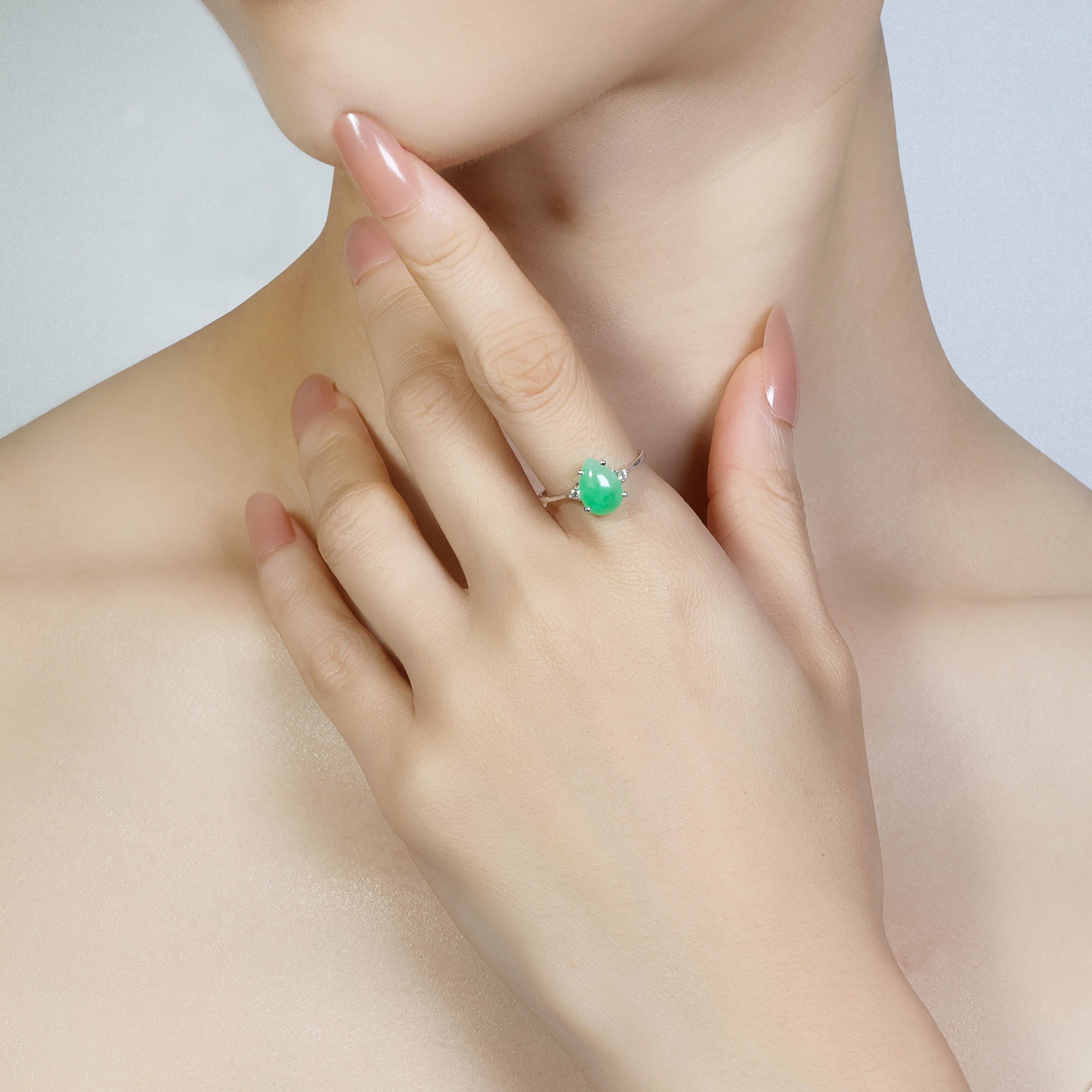 This exquisite 18K white gold ring features a stunning 1.33ct pear-shaped jade as its centrepiece, radiating a rich green hue that embodies elegance and tradition. Flanking the jade are two round brilliant diamonds with a total carat weight of
