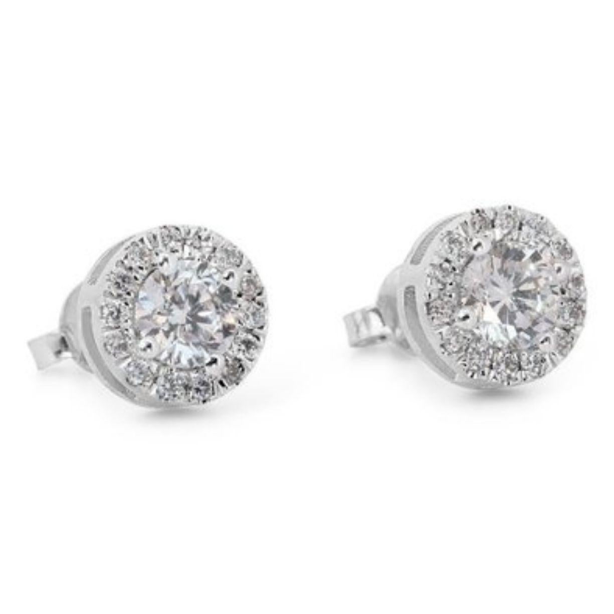 Embrace radiance with these breathtaking 1.14 carat halo diamond earrings, meticulously crafted in gleaming 18K white gold. Each earring features a mesmerizing D color (highest color grade!) Round Brilliant center diamond boasting near-flawless VVS1