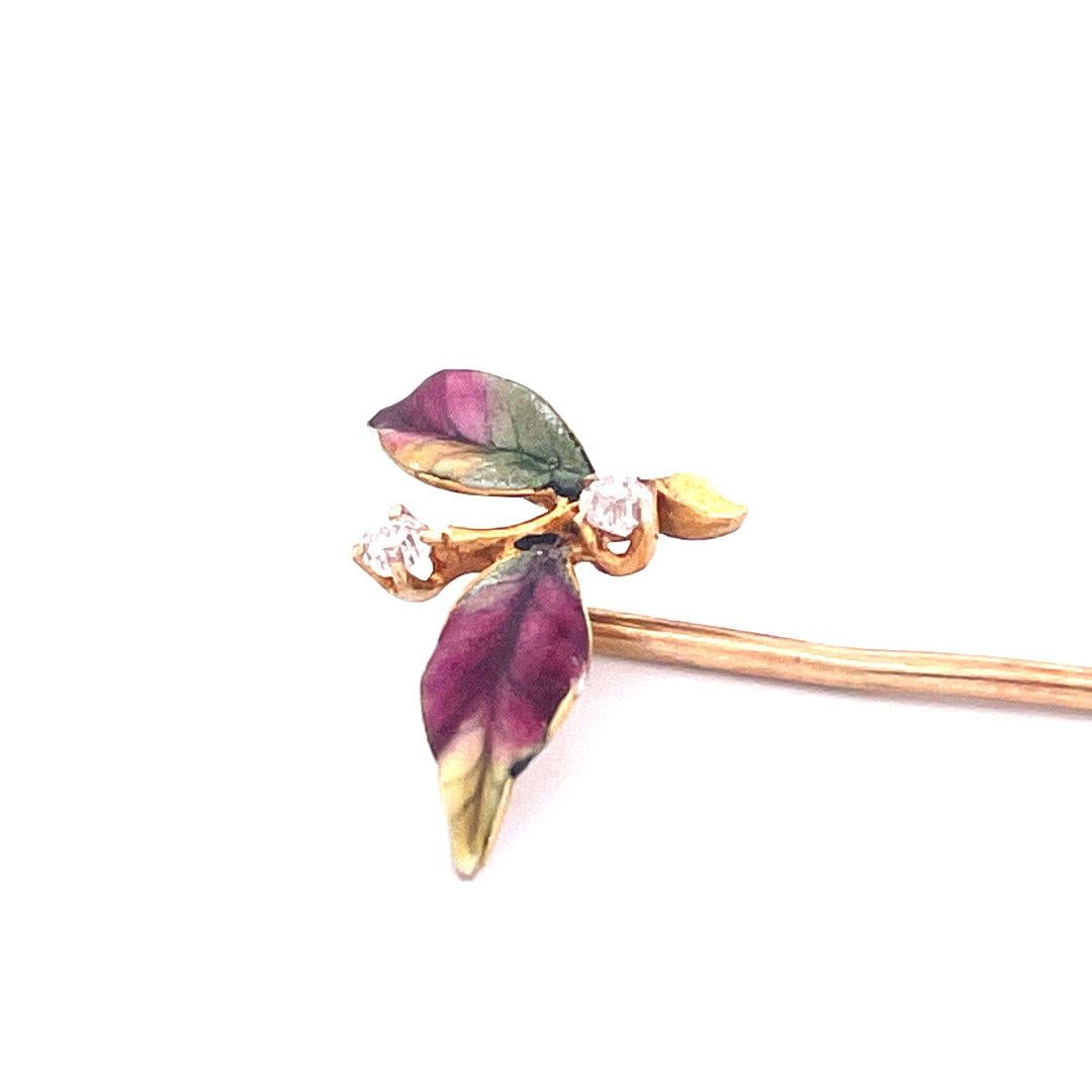 Adorn yourself with the exquisite beauty of this 14k yellow gold enamel leaf with diamond pin. This charming pin features two intricately crafted leaves connected by a delicate branch, accented with two shimmering diamonds at the top and bottom.