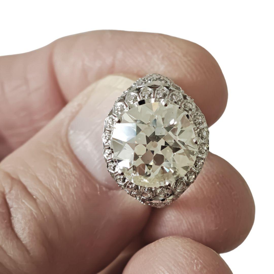 Nous vous présentons une pièce de bijouterie fine époustouflante : Cette bague luxueuse est ornée d'un magnifique diamant central de taille Old European Cut de 6,5 carats qui éblouit par son charme vintage et sa brillance intemporelle. Autour de la
