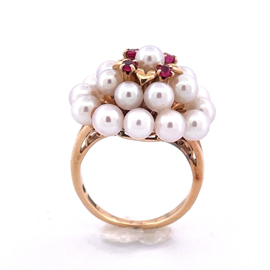 Lassen Sie sich von unserem Ring aus 18 Karat Gelbgold mit Mikimoto-Perlen und Rubinen verführen. In der Mitte befindet sich eine atemberaubende Ansammlung von 21 schimmernden Perlen. Den oberen Abschluss bilden vier zarte Goldblätter, die jeweils
