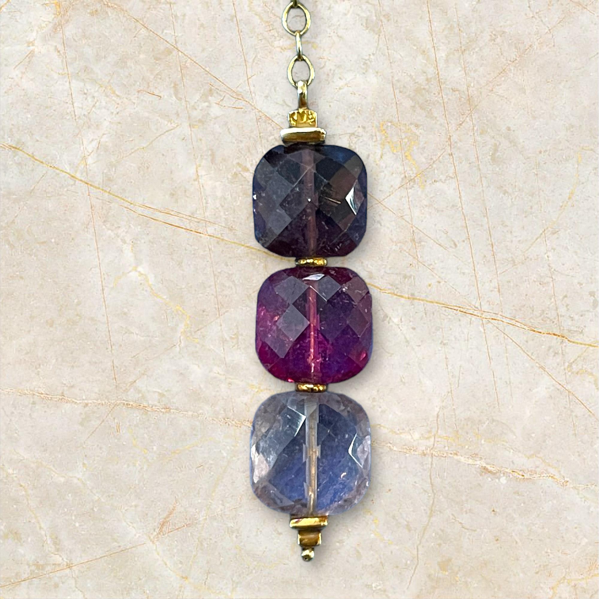 Questa squisita collana in oro giallo 18 carati mette in mostra tre vibranti gemme, scelte con cura per il loro colore e la loro limpidezza. Il design del ciondolo presenta un'armoniosa sfumatura dal viola scuro al rosa intenso, fino al blu tenue,