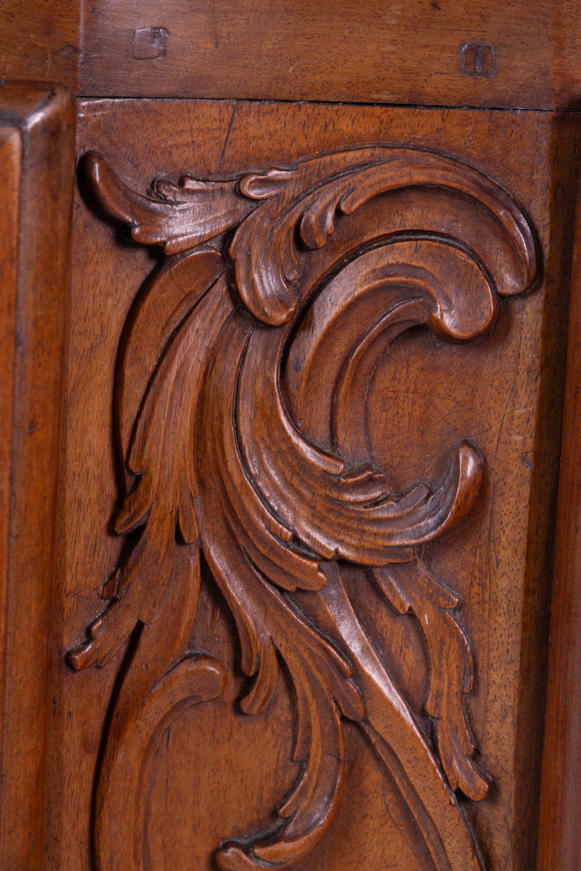 Country French 18th century Lyonnaise carved walnut two door cabinet with original escutcheons, and hinges, adorned with heavy open work carving coming down from center to the apron, and on the legs with scroll feet. The cabinet has a contoured