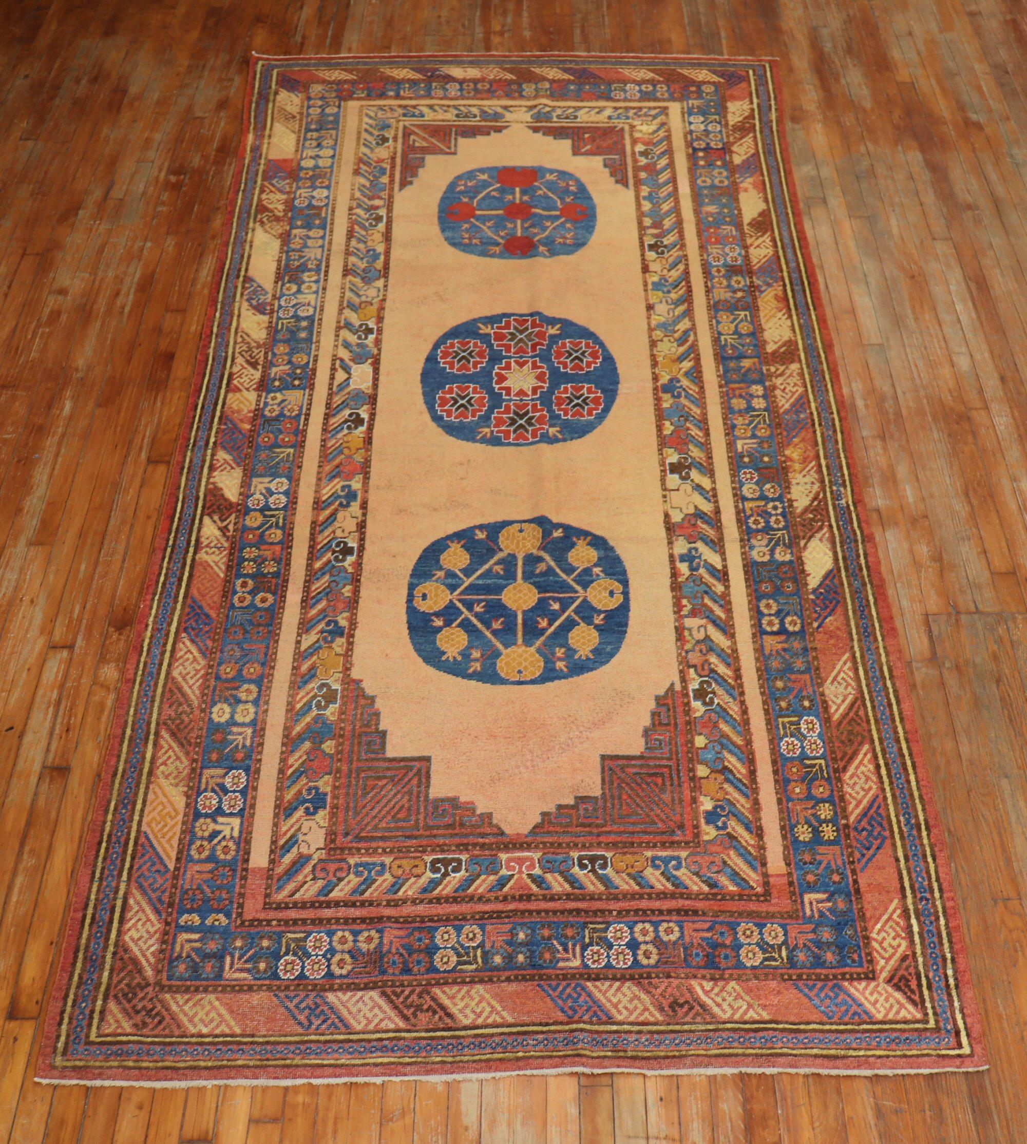 Early 20th century colorful antique Khotan gallery rug. The field is a bone color, denim blue, rust accents are dominant. 

Measures: 5'8
