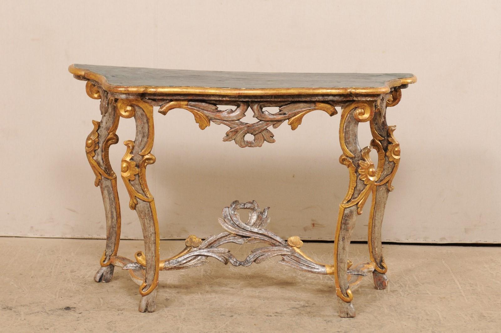 An Italian carved and gilded console table with faux marble top from the 19th century. This antique console table from Italy features a faux-marbled top, nicely carved and pierced skirt, and raised upon four curvaceous and slender legs, wrapped with