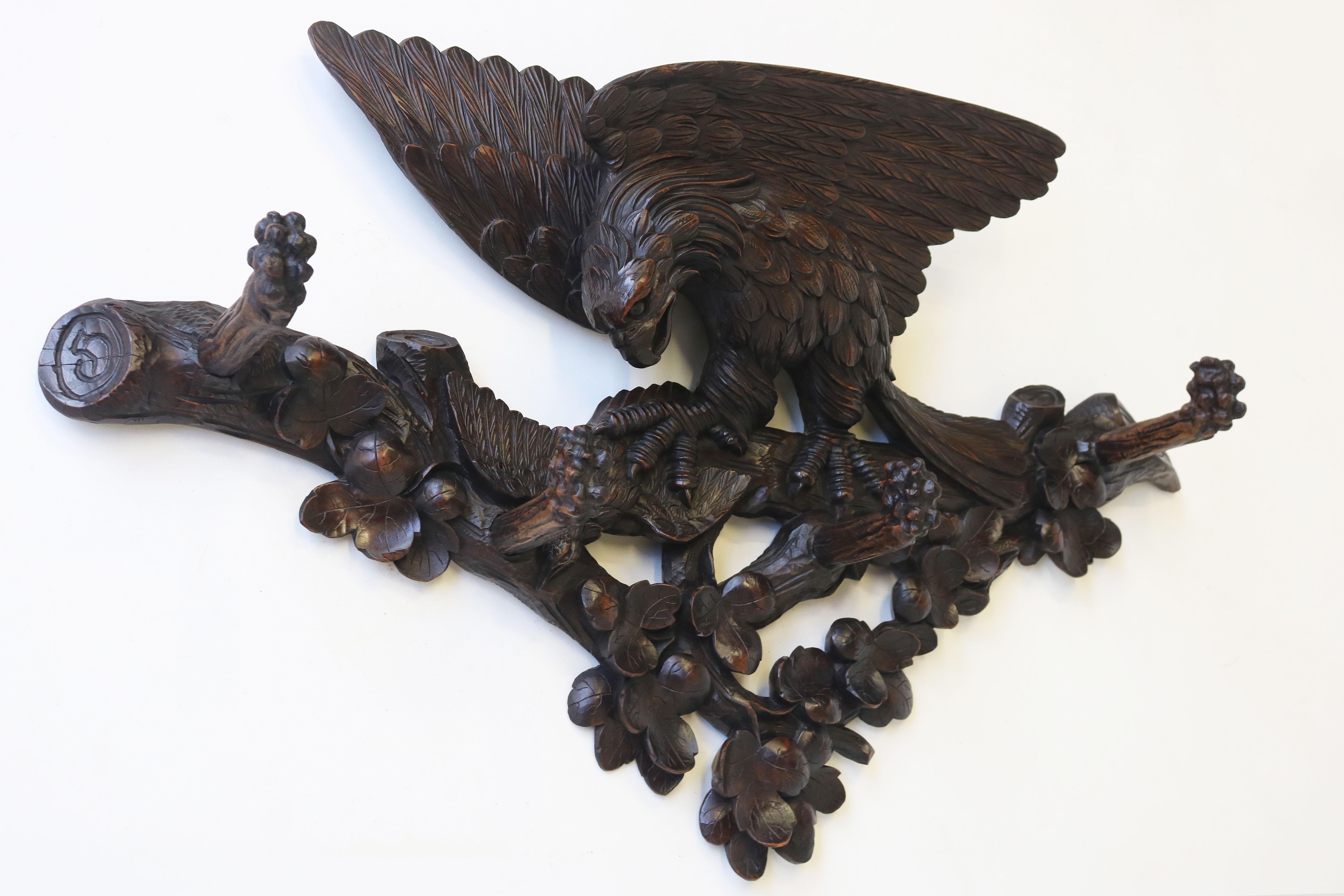 Exquisite & most impressive! This 19th century Swiss Black Forest eagle coat rack from carved wood. Highly detailed model with 4 hooks.  The coat rack shows a scene of an eagle holding down its prey. Richly decorated with branches, leaves. carved