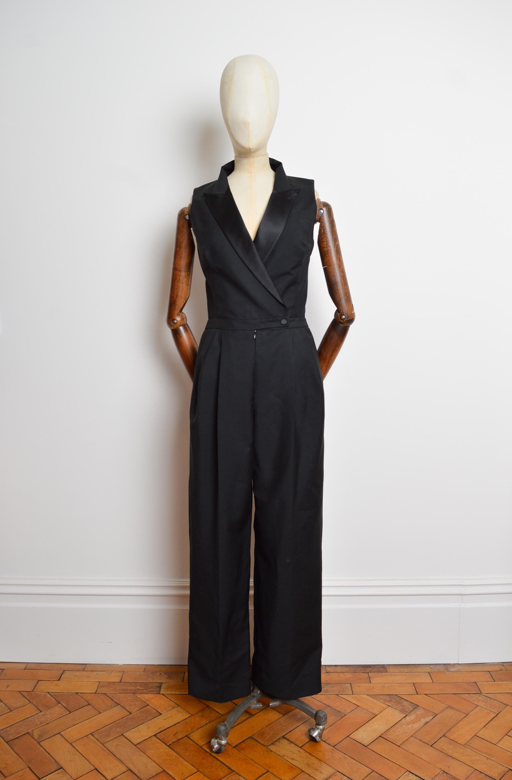 Exquisite 2011 Alexander McQueen Black Tuxedo Suit Tailored Jumpsuit.
Featuring shiny lapels, nipped waist line, and pockets at the hips. The Garment is fully lined in pure silk. 
Recommended Size; U.K. 6
Measurements are provided in inches (‘’)
Pit
