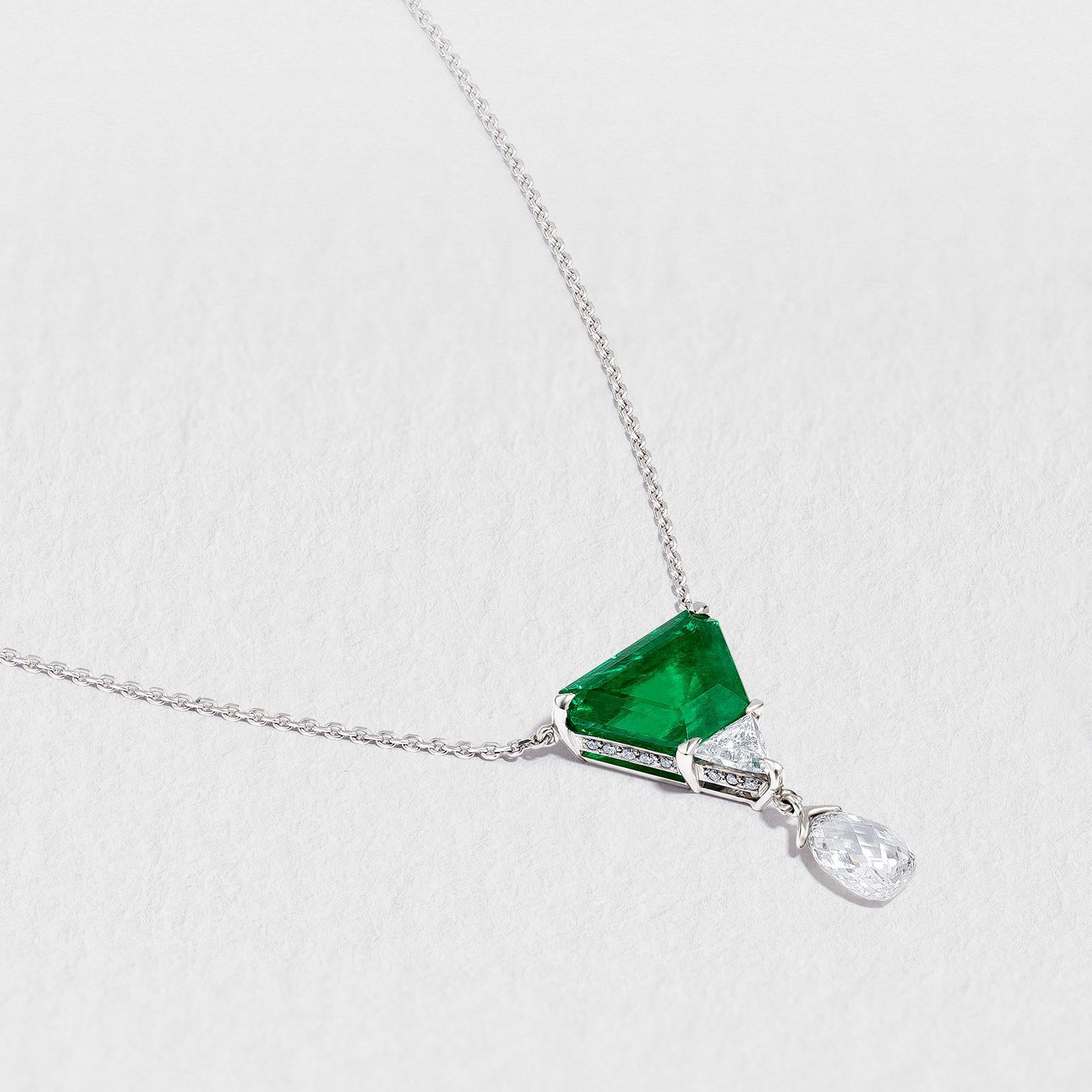 Crafted by hand in the Haruni workshop, this unique necklace features an impressive deep-green Colombian emerald in a shield cut, and a smaller shield cut white diamond. The stones' angular beauty is offset by a delicate briolette diamond