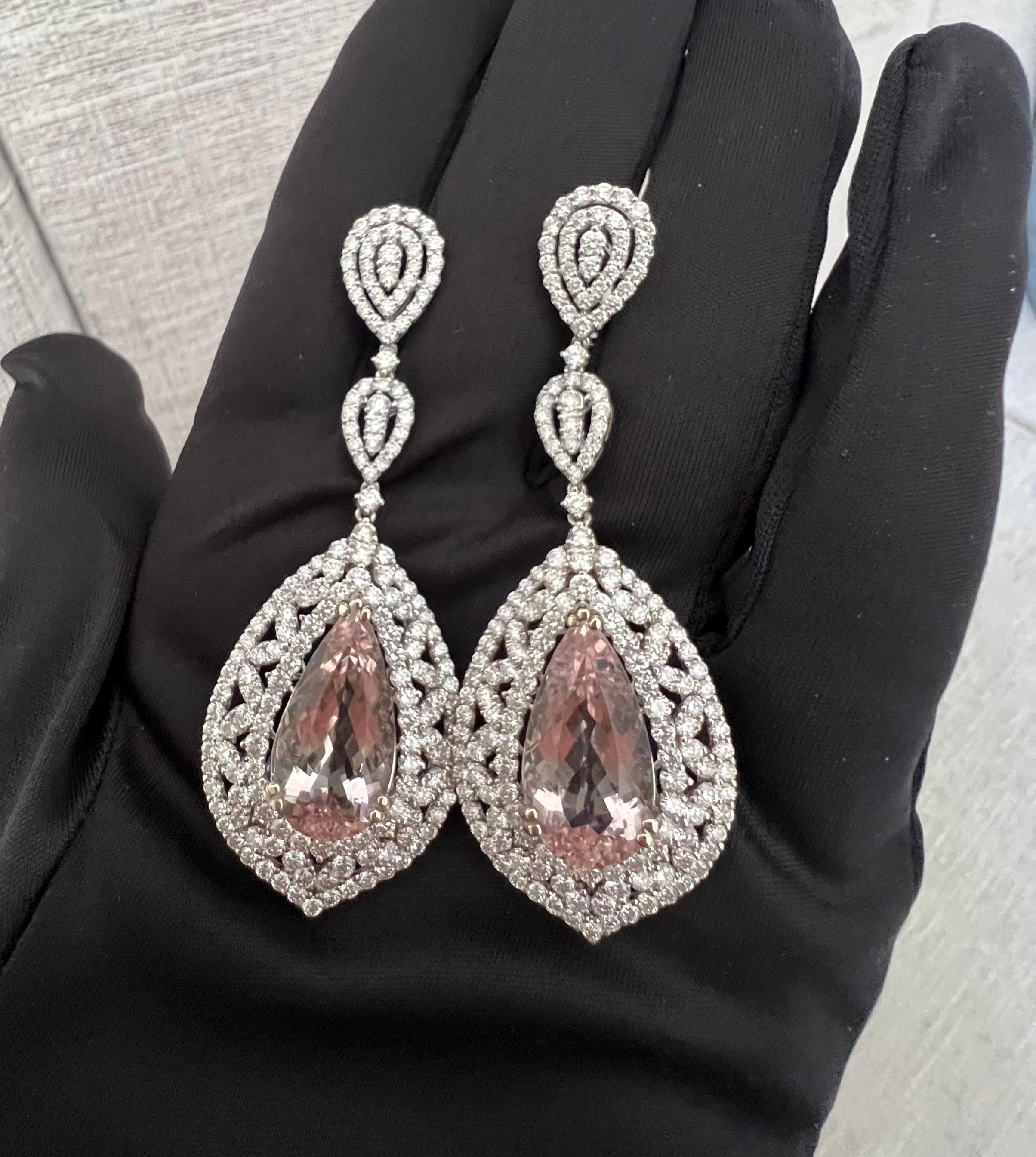 Exquisite pair of 33.85 carat total weight pear shaped brilliant cut pink morganite and diamond earrings are talon prong set in 18 karat white gold above a mesmerizing three layer pear shaped diamond halo of round brilliant diamonds set in between a