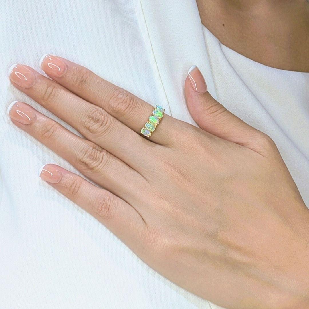 Questo elegante anello con 5 pietre di opale mette in mostra l'ipnotico gioco di colori degli opali ovali naturali, ognuno dei quali brilla di una lucentezza arcobaleno che si sposta meravigliosamente con la luce. Incastonato in caldo oro giallo 18