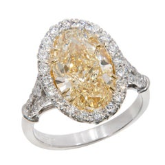Exquisito anillo con halo de platino y oro de 18 quilates con un diamante ovalado amarillo «Fancy» de 6,22 quilates en total