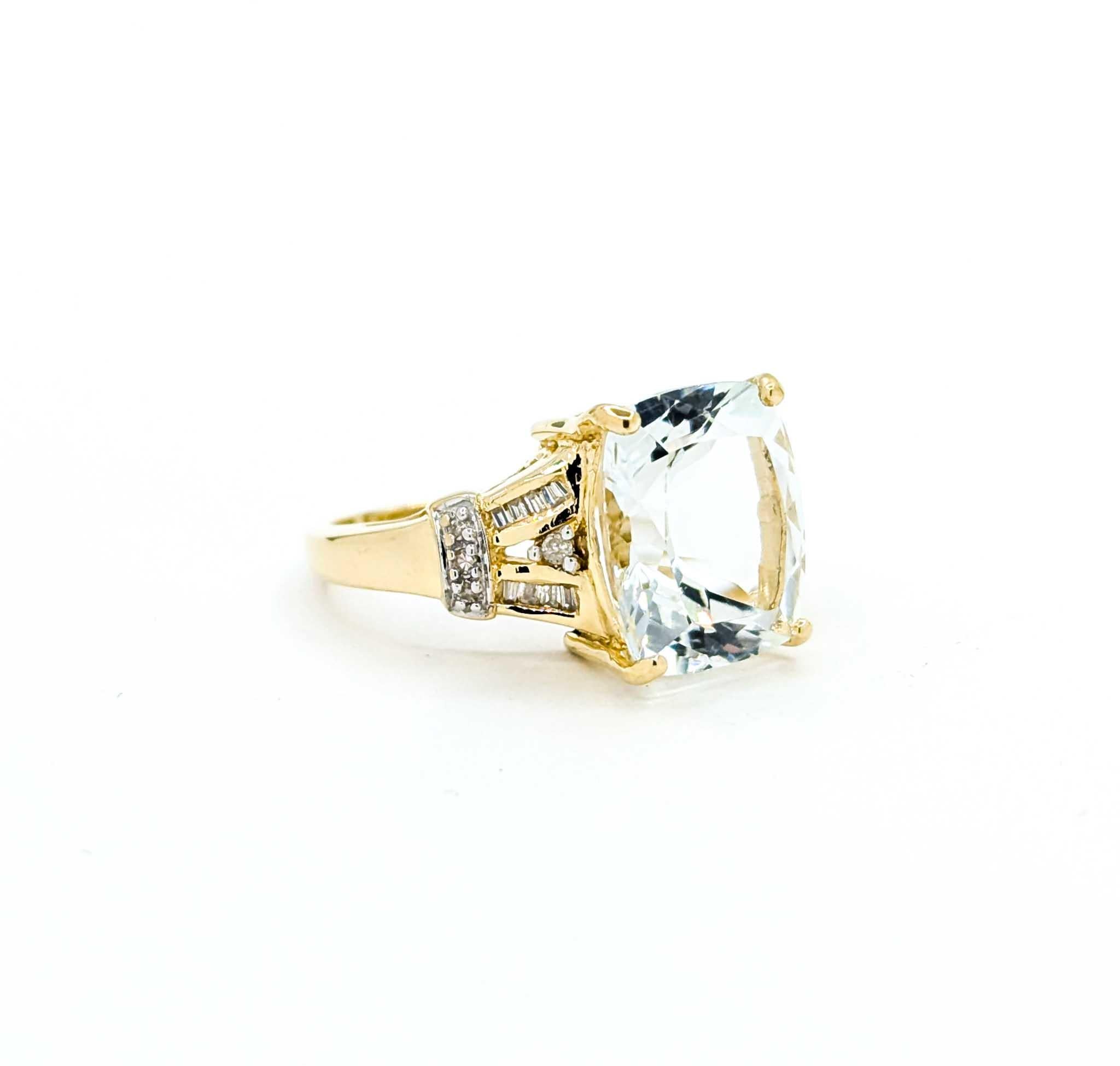A striking statement of elegance, this ring showcases a vibrant 7ct cushion-cut green prasiolite, securely set in a ribbon-inspired filigree mounting. Crafted in rich 14k yellow gold, the design is further enhanced with .10ctw of sparkling round and