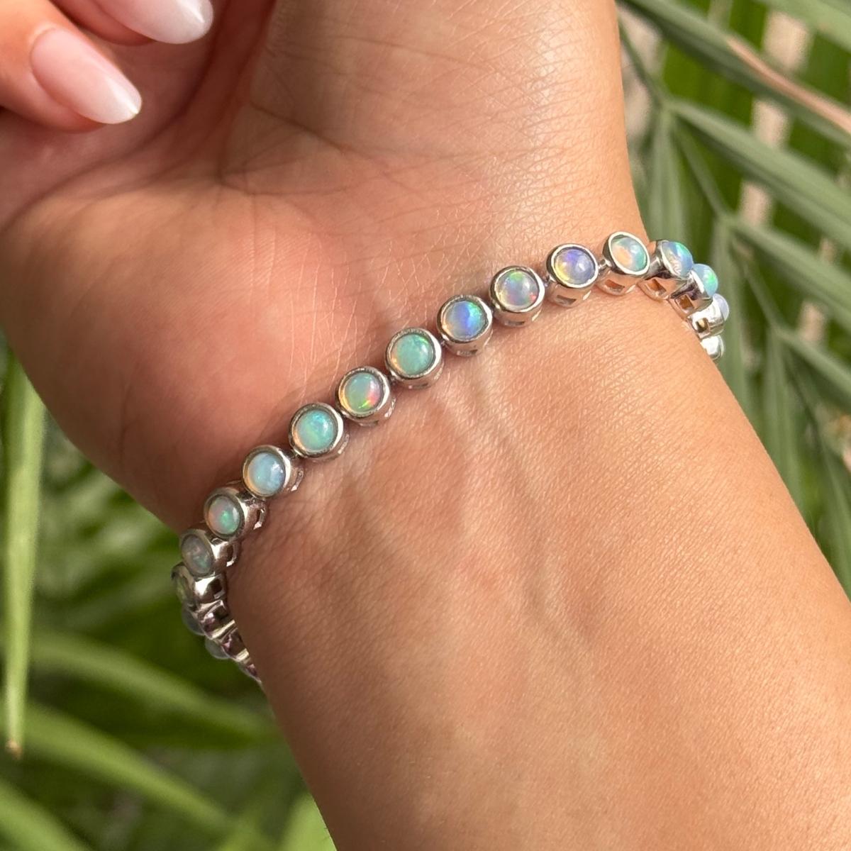 This Ethiopian Opal Cabochon Tennis Bracelet exquisite Ethiopian opal tennis bracelet, meticulously handcrafted in 925 sterling silver. Each round bezel-set opal glows with a mesmerizing play of color—flashes of green, blue, pink, and gold dance