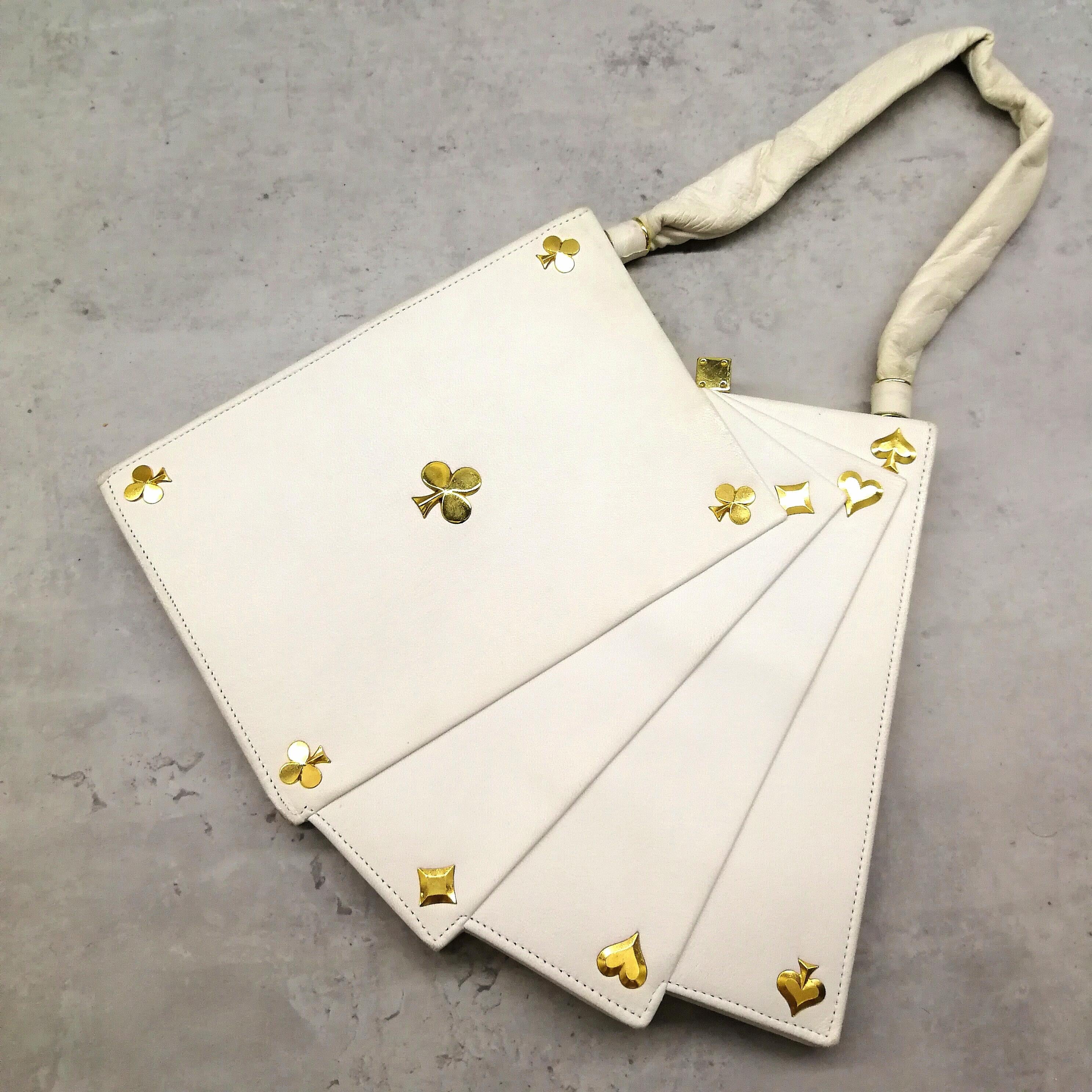 A wonderful 'Hand of Cards' handbag by Anne-Marie, in white kid leather, with gilt highlights(suits of cards) and a clever clasp, in the shape of a very realistic 'dice'. The bag is signed inside 'Anne-Marie, 228, Rue de Rivoli, Hotel Meurice,