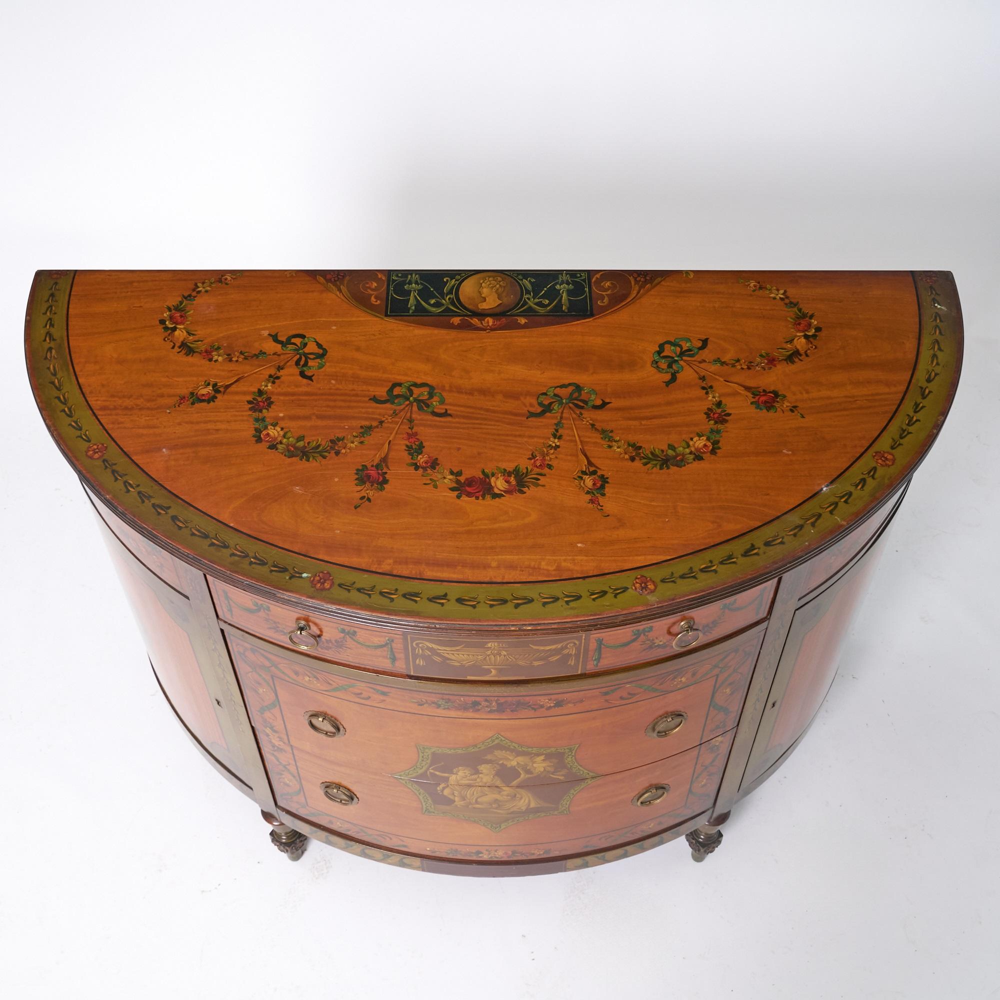 Ce magnifique buffet ancien en bois satiné peint à la main dans le style Adams, également idéal comme crédence, allie une élégance intemporelle à un savoir-faire raffiné. De forme gracieuse, il comporte trois tiroirs frontaux dotés d'élégantes