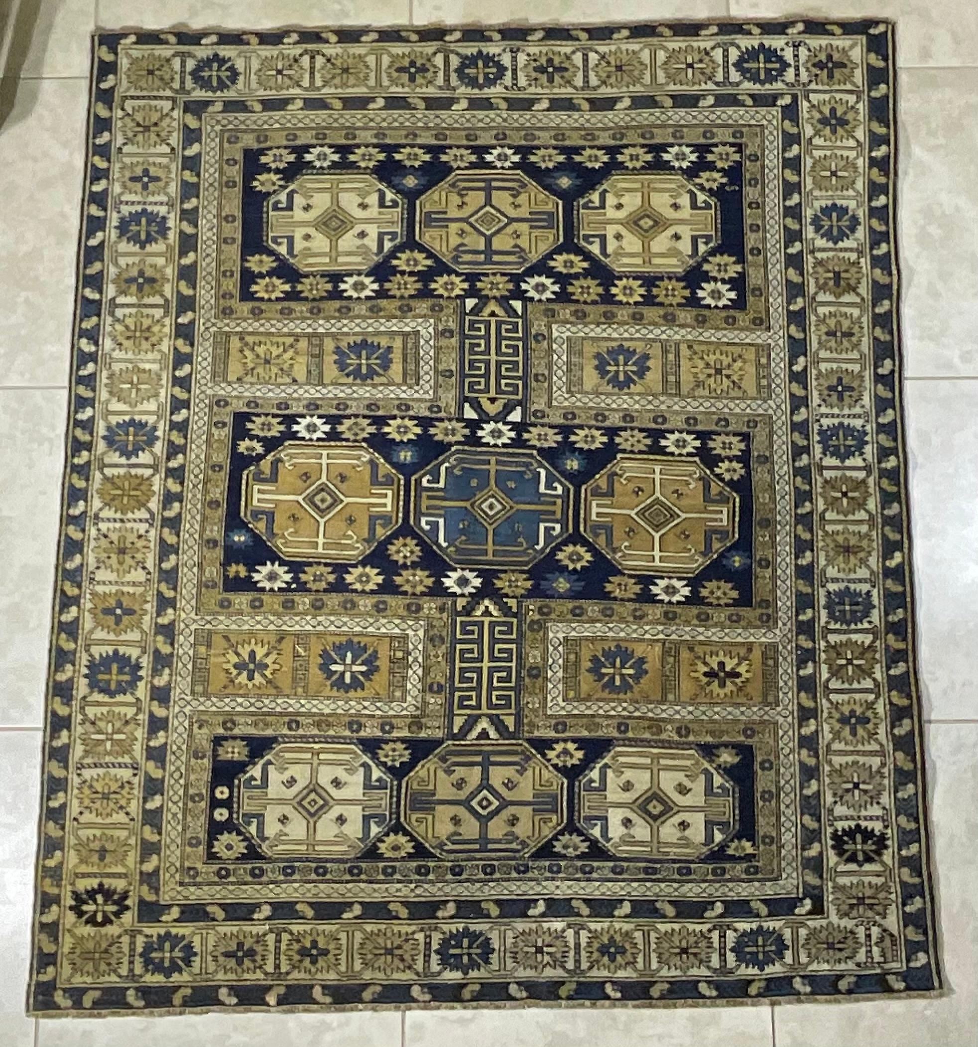 

This captivating rug features a harmonious blend of deep navy blue, rich gold, and subtle ivory tones, creating a visually striking and sophisticated aesthetic. The design showcases a series of geometric medallions and intricate motifs,