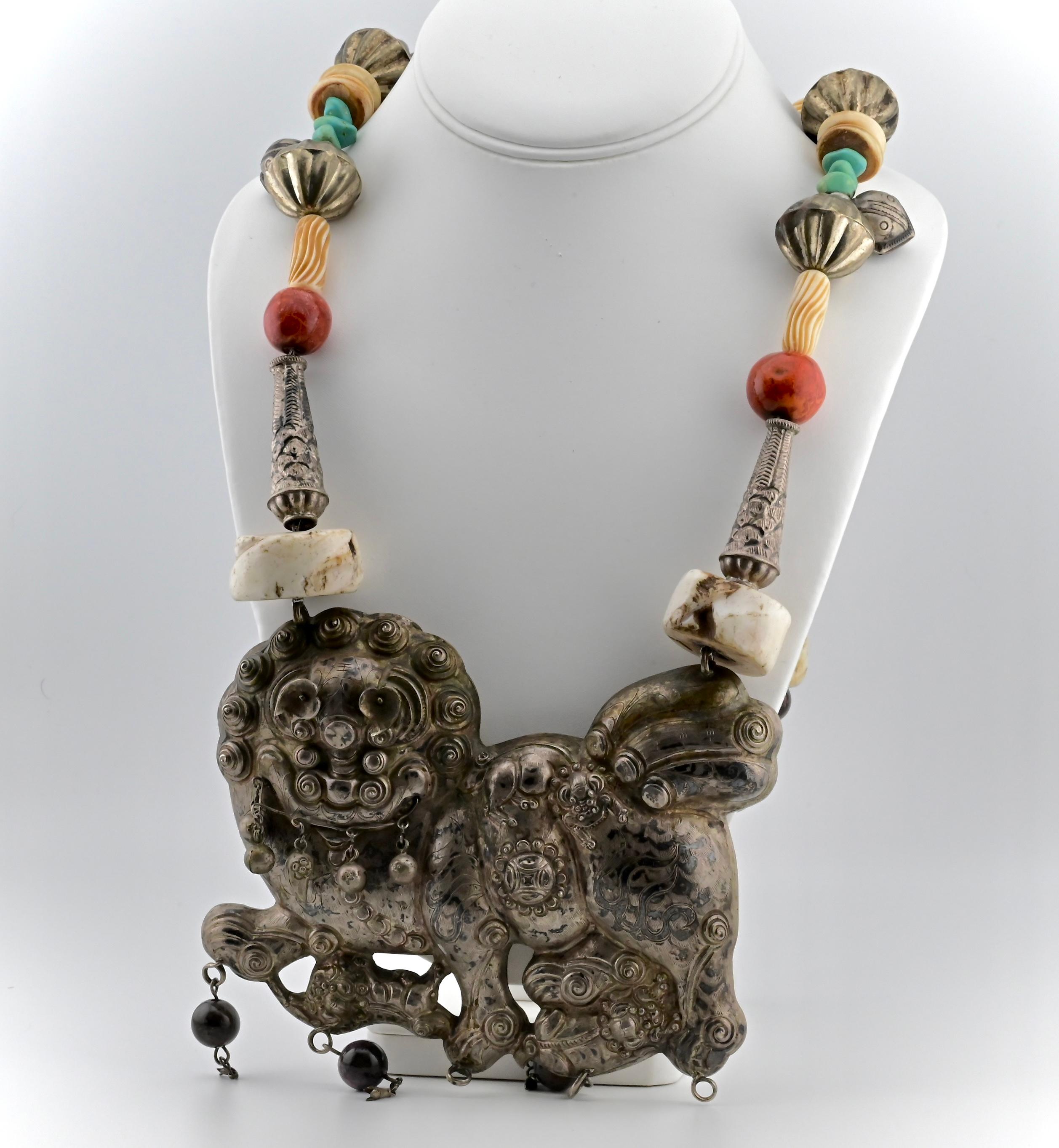 This is a unique Chinese foo lion silver tribal necklace. The necklace has a range of different materials including bone, coral, silver, turquoise, etc.  It weighs a total of 482 grams, and is 22 inches long. Each strand connecting to the lion is 17