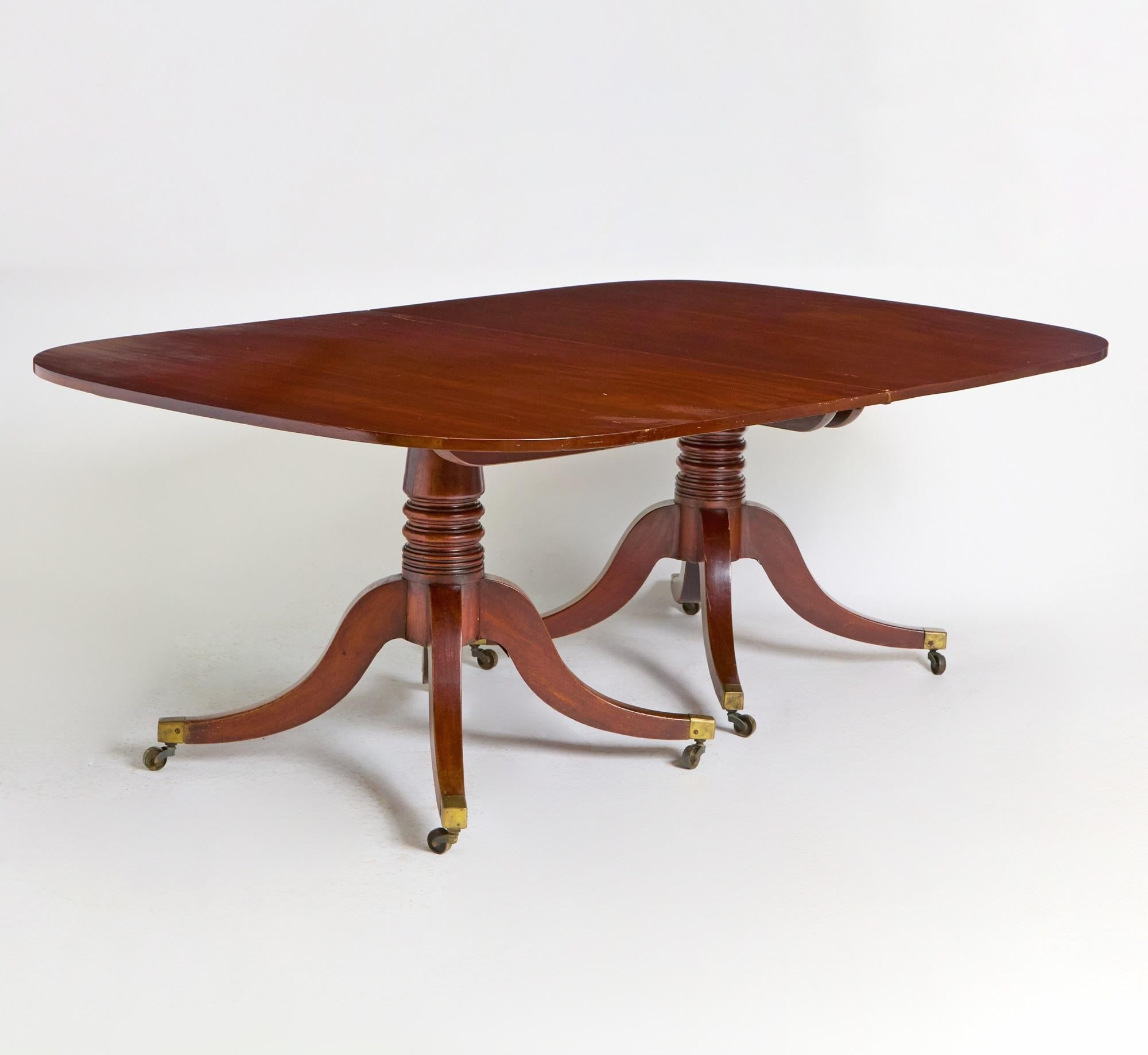 Cette exquise table de salle à manger anglaise antique en acajou de style George III respire la sophistication et le raffinement classique, témoignant de l'habileté de l'artisanat du début du XIXe siècle. Magnifiquement construite en acajou, la