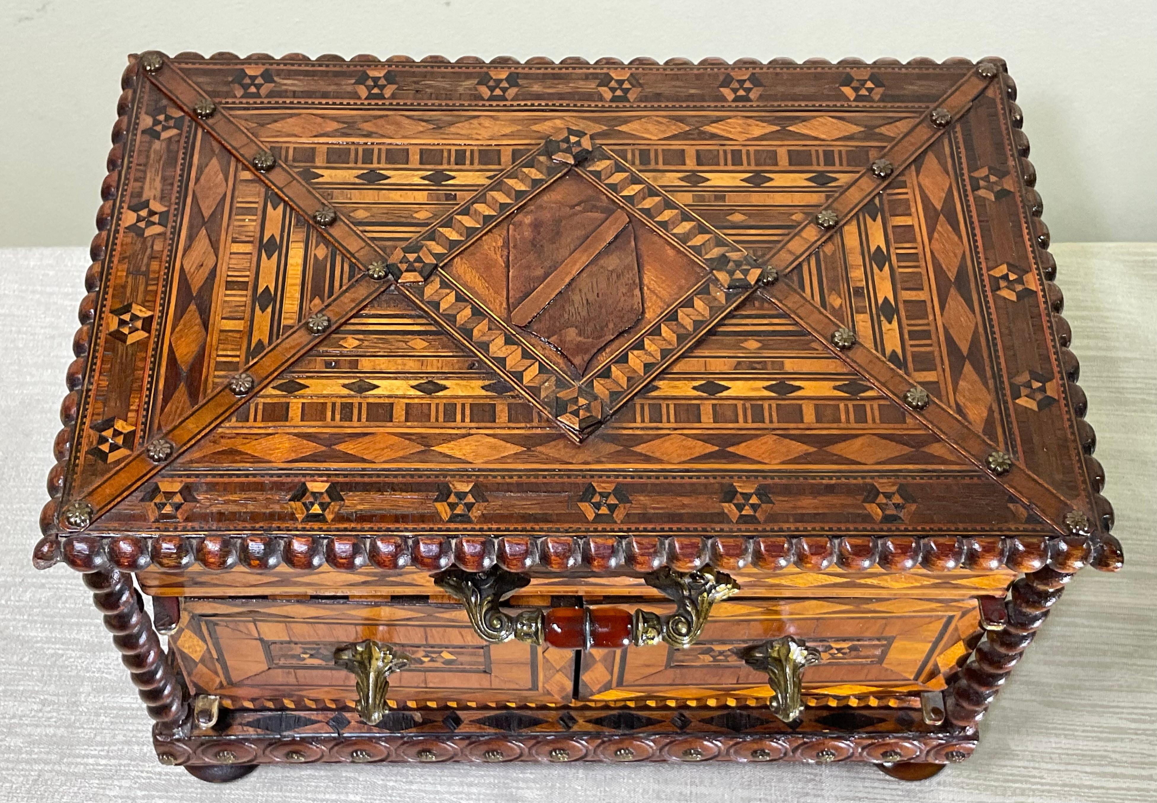 This exquisite antique jewelry box is a true masterpiece, showcasing intricate marquetry work and exceptional craftsmanship. Its geometric design on the lid, created using various types of wood in a harmonious blend of colors and textures, is
