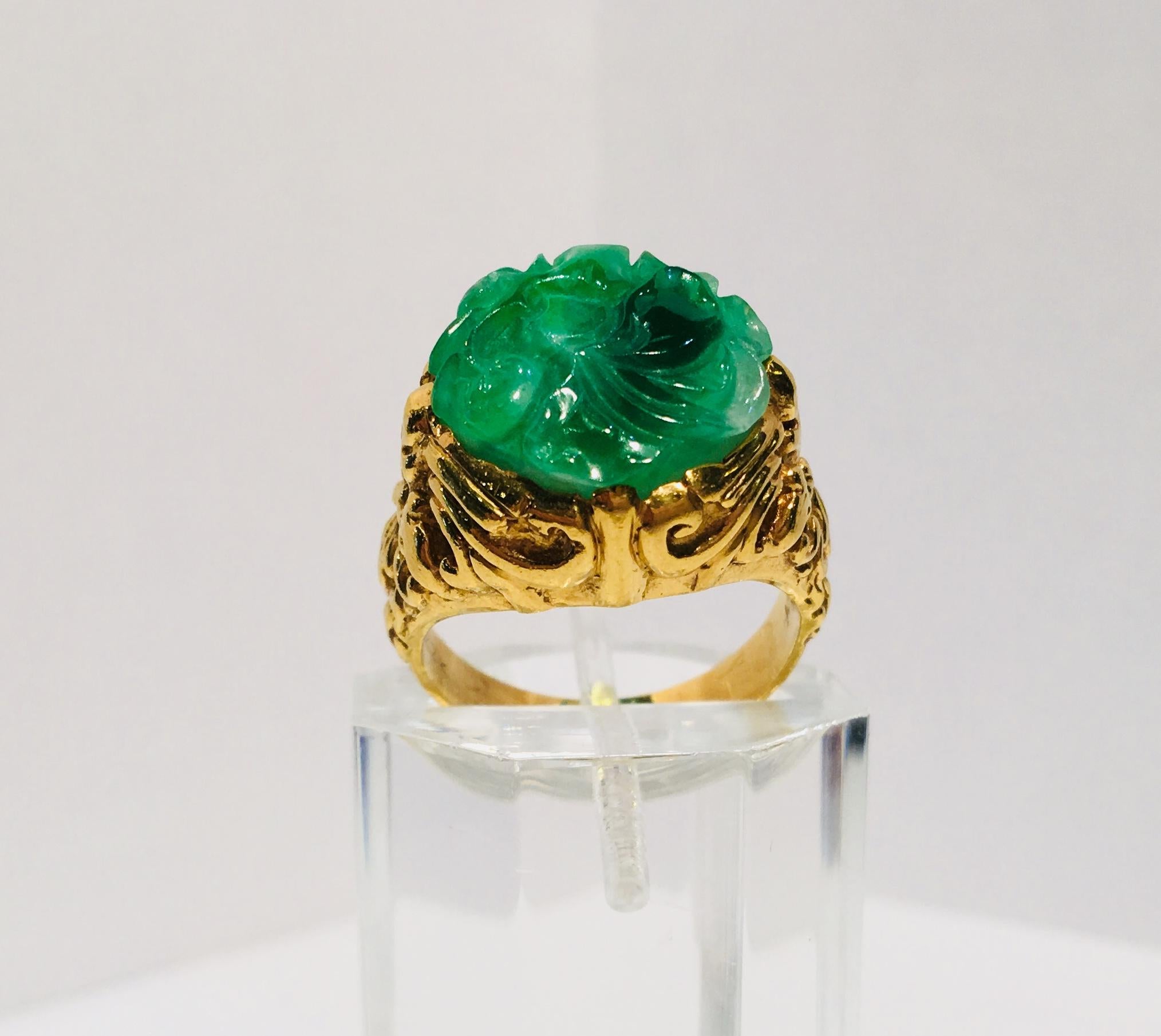 Beautifully detailed, estate, 22 karat heavy yellow gold ring features a bezel-set, variegated, apple green, richly carved, natural jade flower.  The gold work in the mounting includes deeply textured swirls and curlicues.  

Jade flower measures