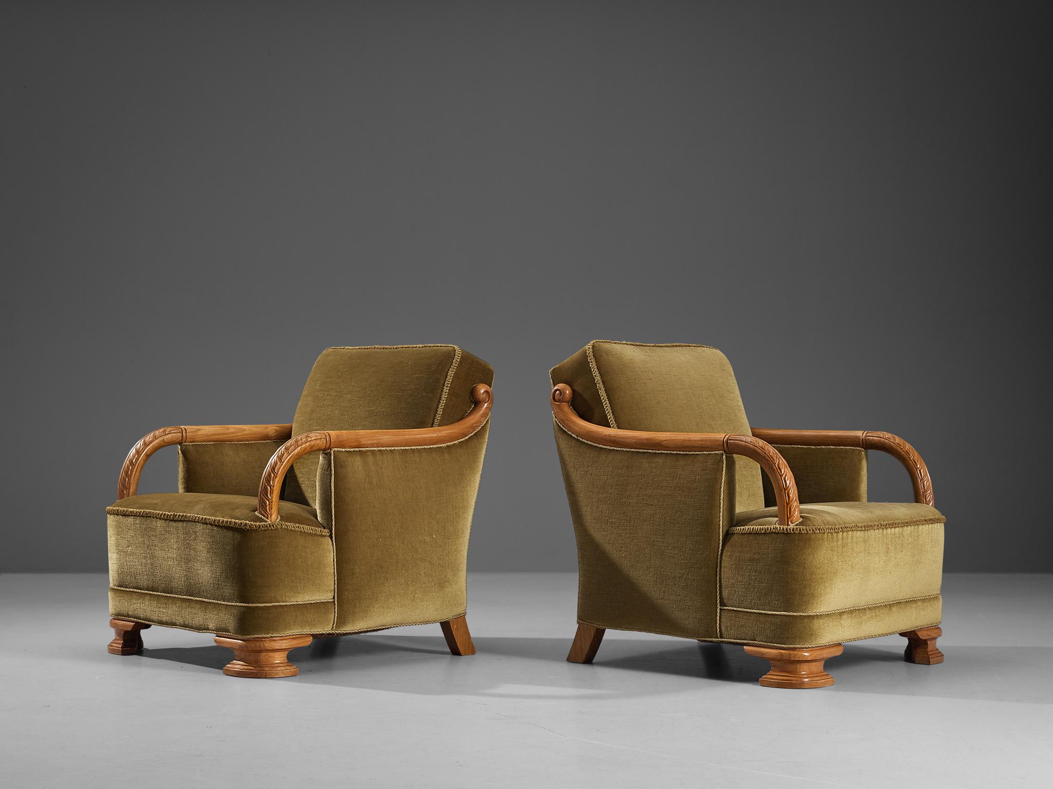 Pair of easy chairs, velvet, elm, Denmark, circa. 1940 

This rare pair of lounge chairs of Danish origin comes with an olive green velvet upholstery that beautifully blends in with the warm tone of the wooden frame executed in elm. The design is