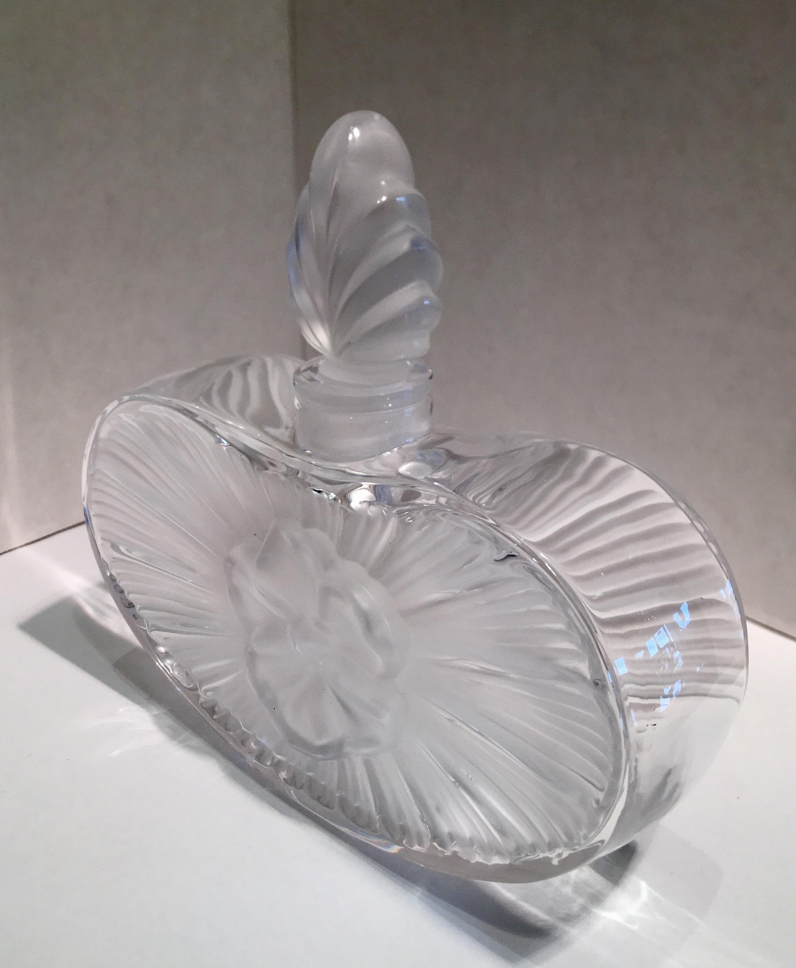 Timelessly elegant, Art Deco style, handcrafted lead crystal perfume bottle by renowned French perfume bottle maker, Lalique, features a pleasing, rounded heart shape bottle with a three dimensional pansy flower in the centre on both sides. Bottle