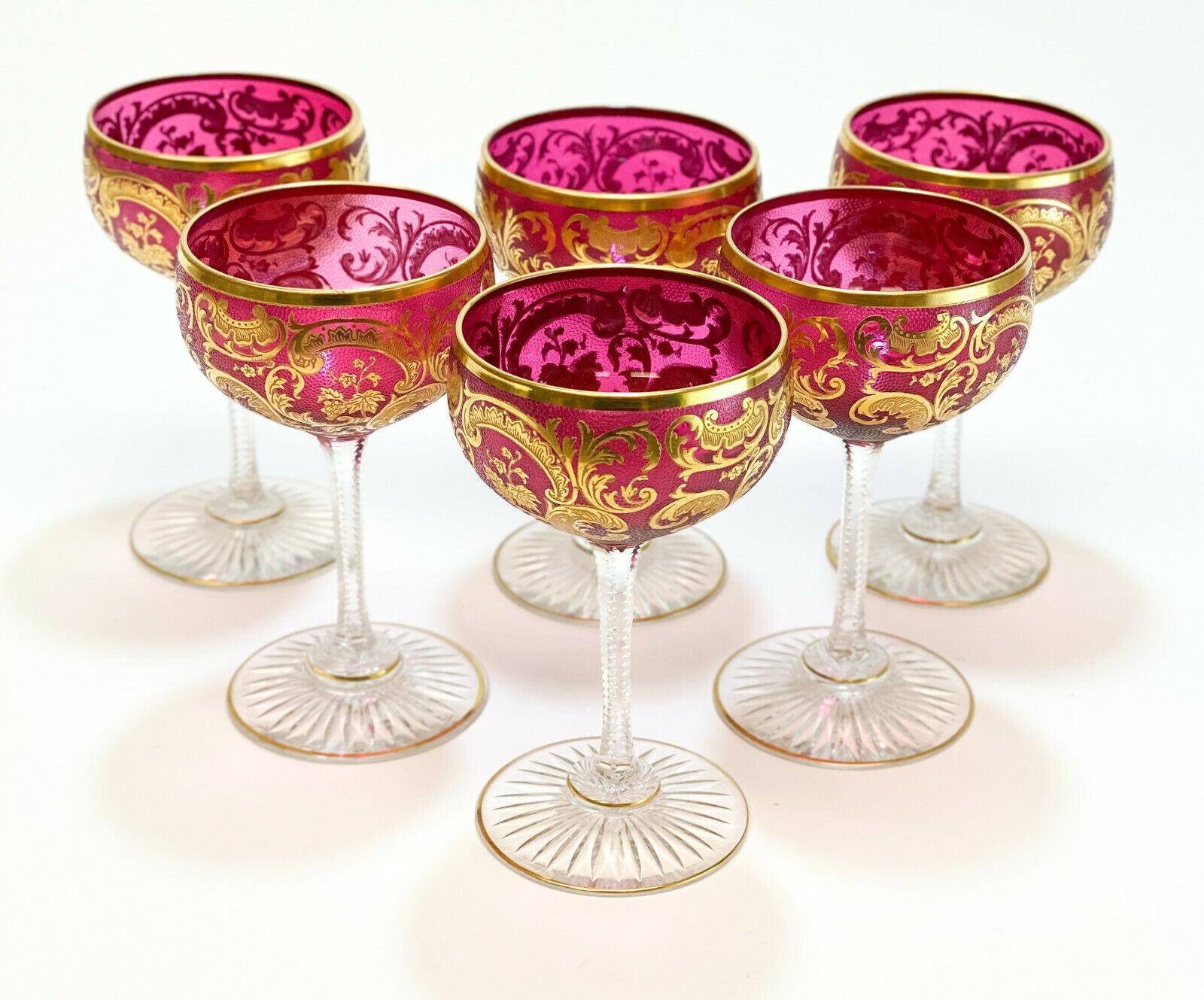 7 exquisite Baccarat cranberry red and gilt wine glass goblets. Gold encrusted foliate scroll designs to the exterior with cut starburst designs to the base. 

Weight approximate, 3 lbs 

Measures approximate, 2.75 inches diameter x 4.5 inches