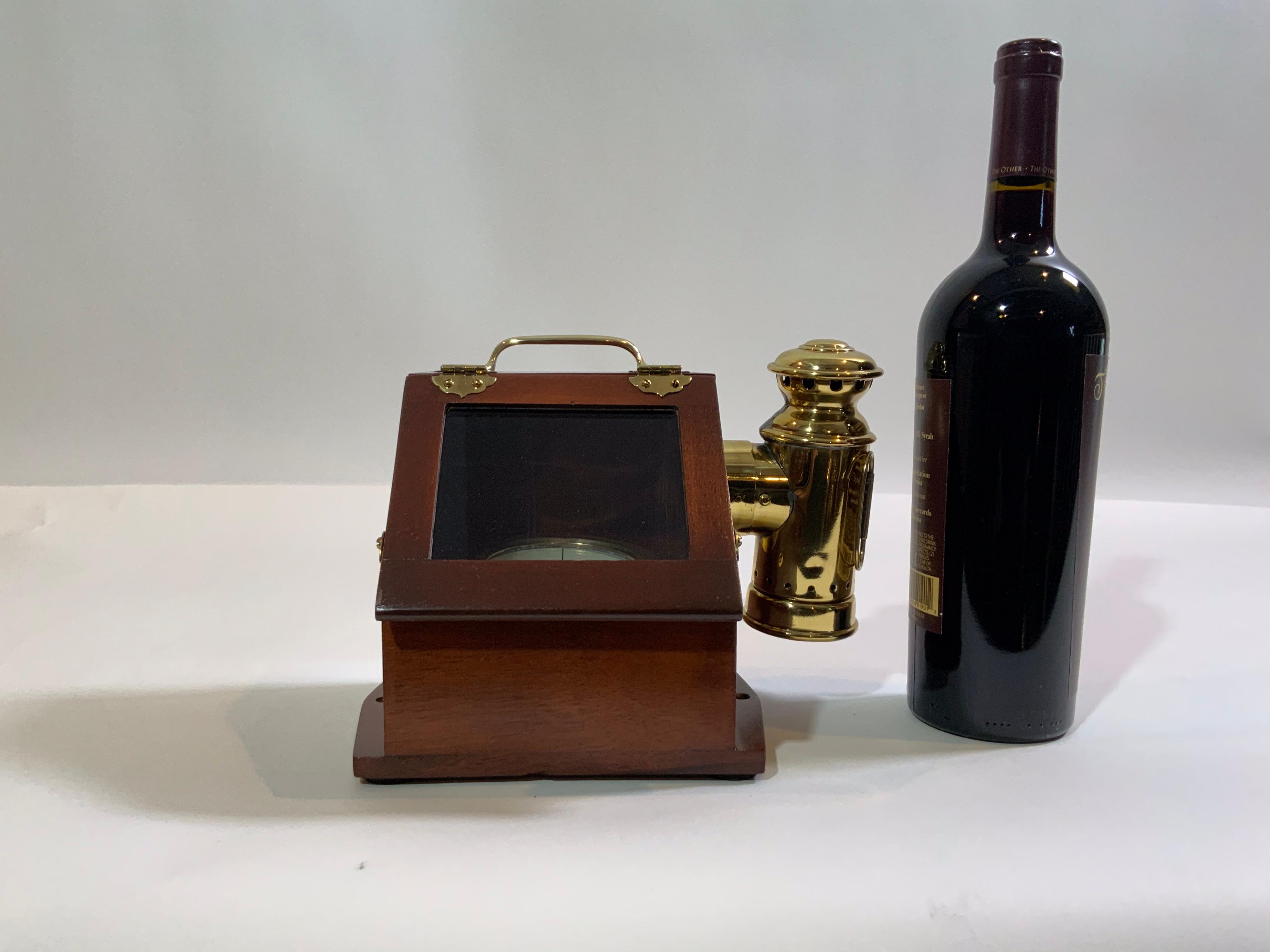 Solid brass yacht compass fitted to a very fine varnished binnacle box with brass hinges and glass door. Also fitted with a varnished brass sidelight with original burner. Circa 1890.

Overall Dimensions: 7