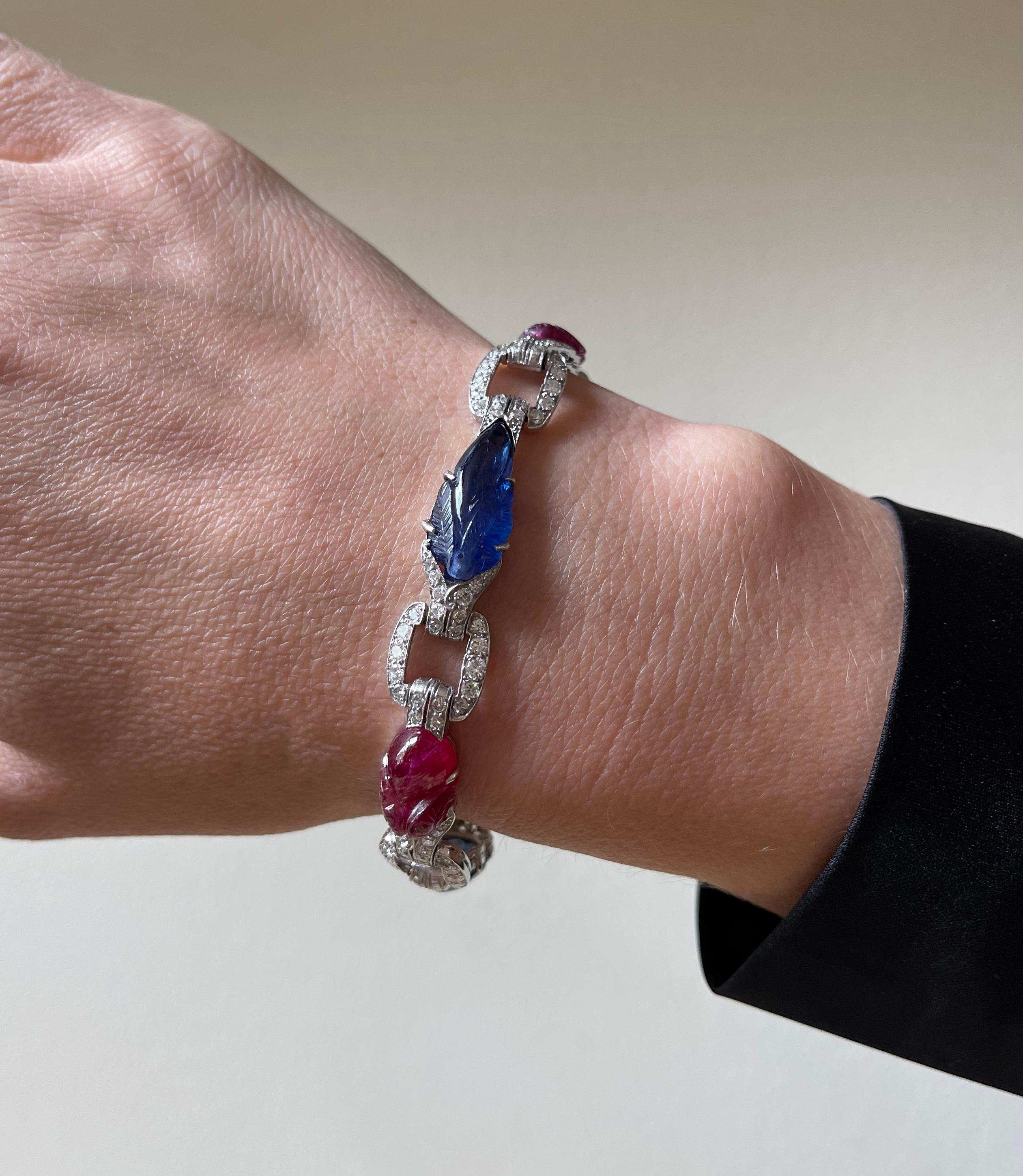 Exquisite and unique 18k white gold bracelet, set with carved rubies and sapphires, surrounded with approx. 2.50ctw in diamonds H/VS-Si. Bracelet is 7