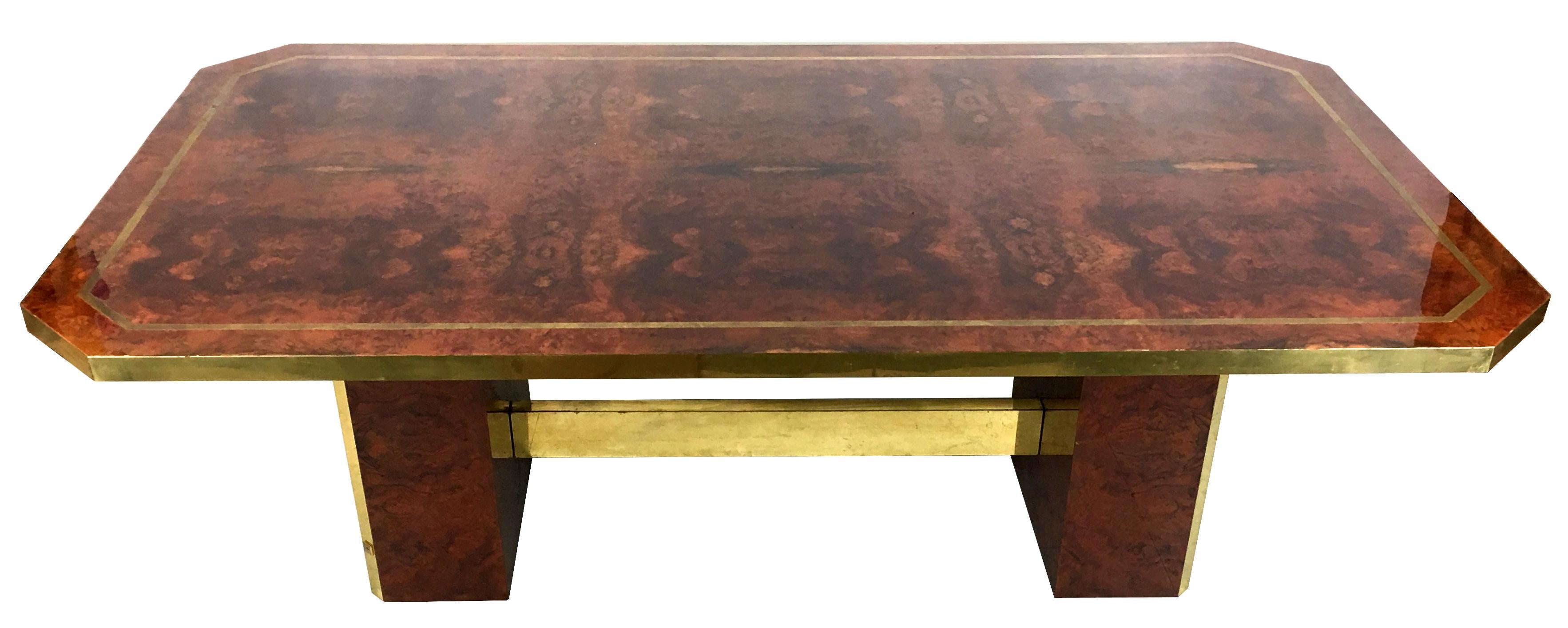 Super chic 1980s dining table in cedar burl with brass trim by Jean-Claude Mahey. The vibrant matched grain burl top is bordered in brass with brass edges and the stretcher is clad in brass. The twin pedestals are also burl, trimmed in brass and the