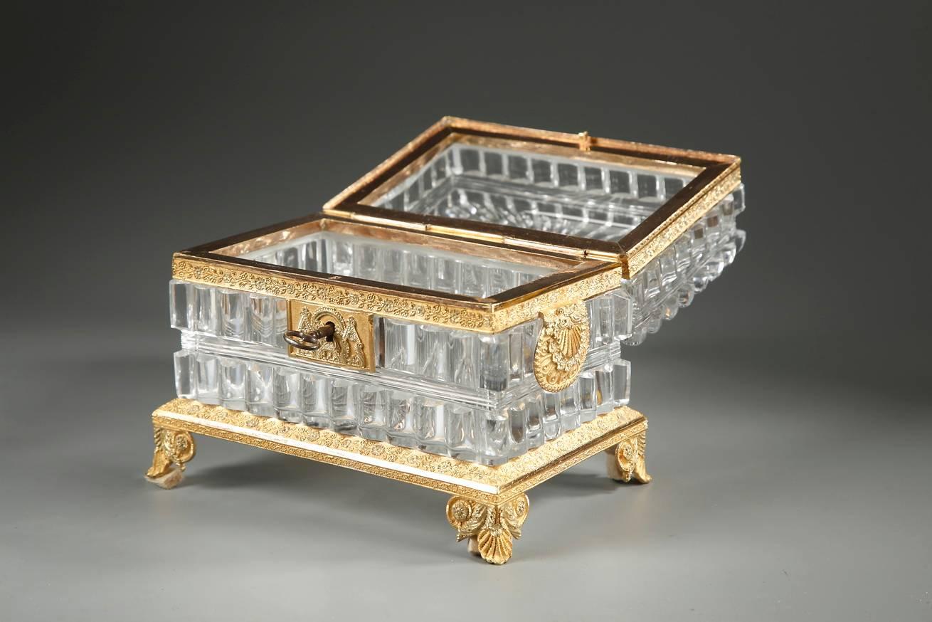 Rectangular cut-crystal? casket? with a rounded facets on the body and a starburst motif on the top of the lid. The ormolu frame and lock plate are very intricately engraved with small flowers, scrollwork, and foliage. Two medallions representing
