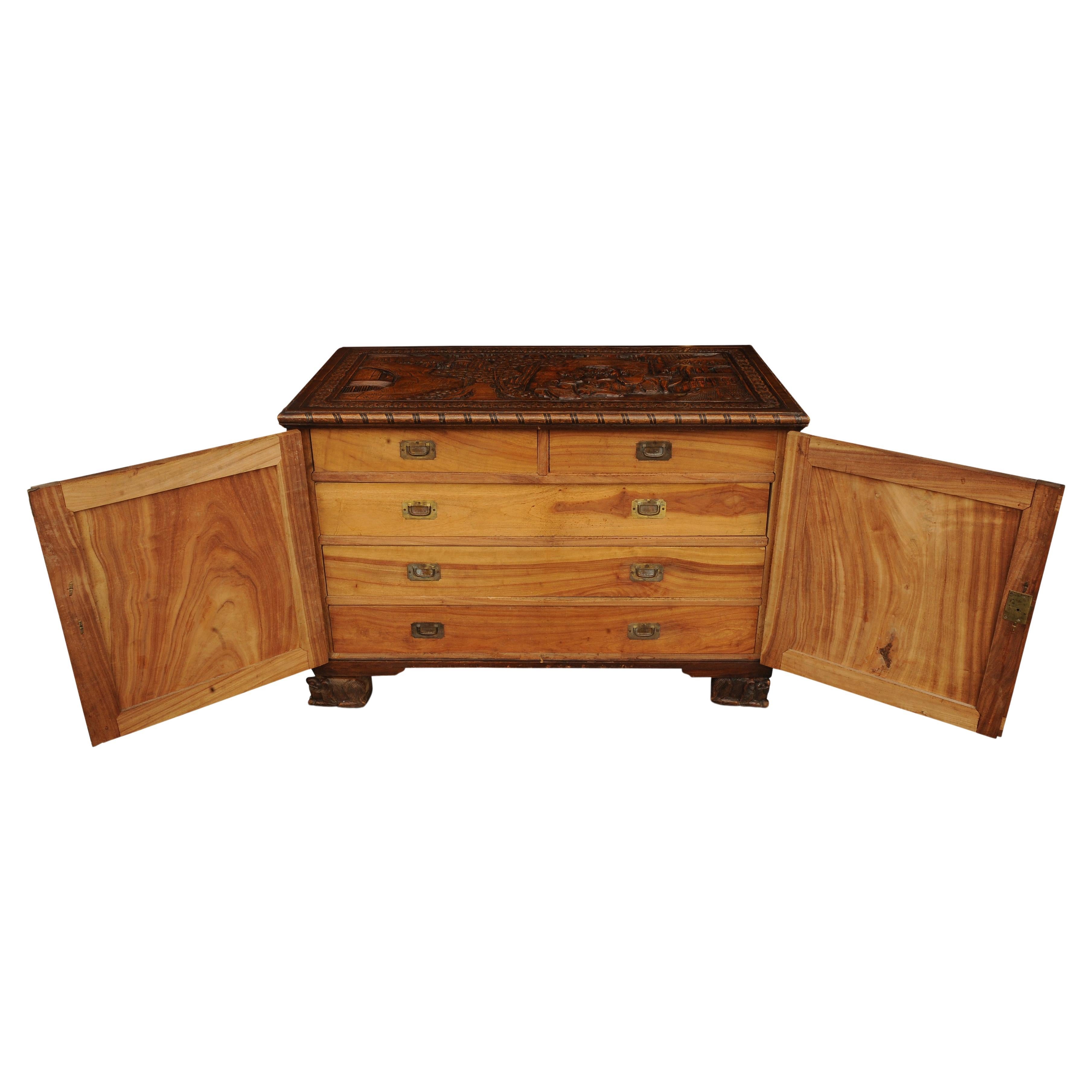 An Exquisite Carved Chinese Export Two Door Camphor Chest With Etched Brass Lock Fitted With A Removable Glass Top. 

Open the two doors to reveal three long, and two short campaign drawers. 

The carving scenes throughout offer a glimpse into life