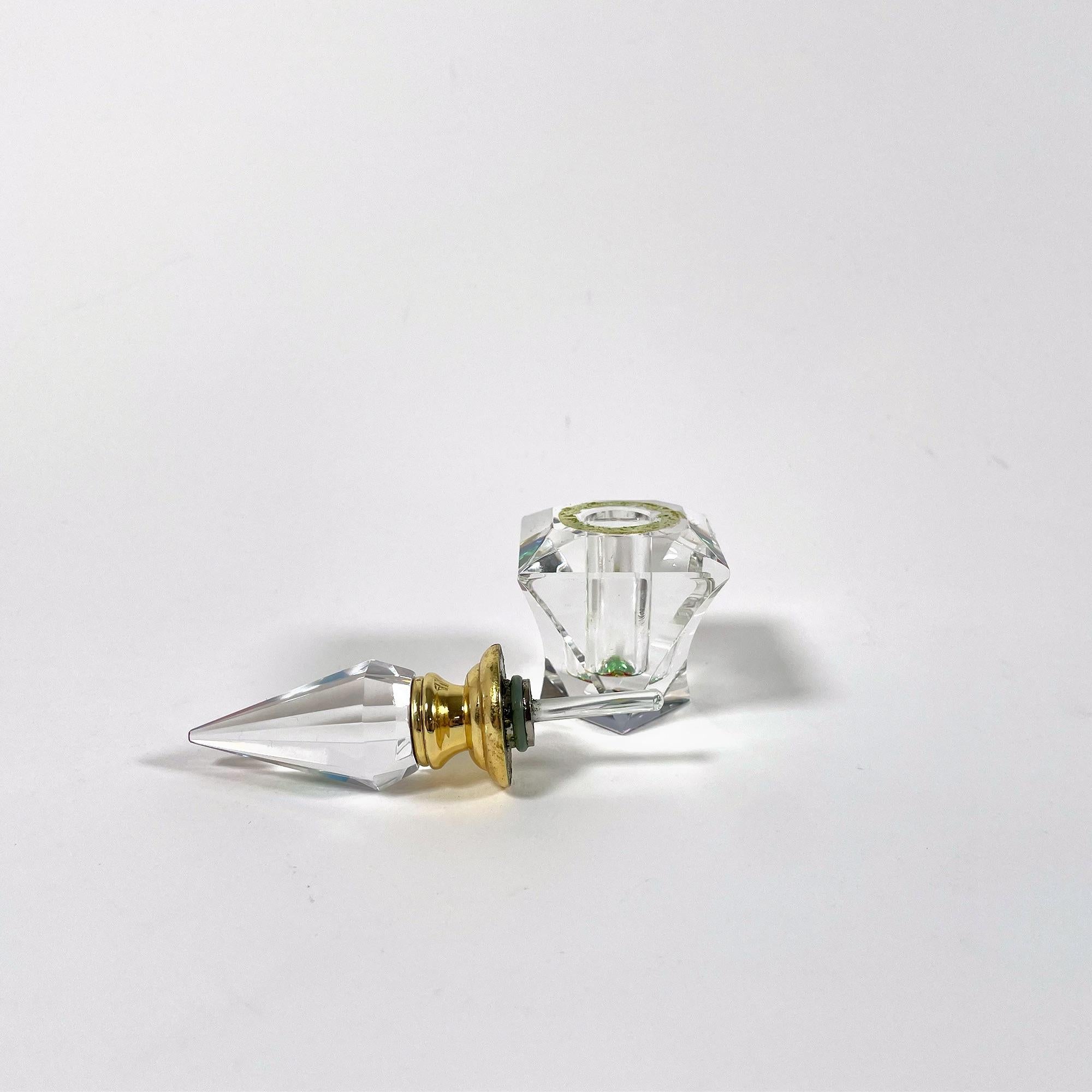 Realza tu tocador o tu colección con este elegante frasco de perfume de cristal tallado de la década de 2000. Con una altura de 10 cm y una base cuadrada de 4 cm, este exquisito recipiente desprende sofisticación y encanto atemporales. Aunque no