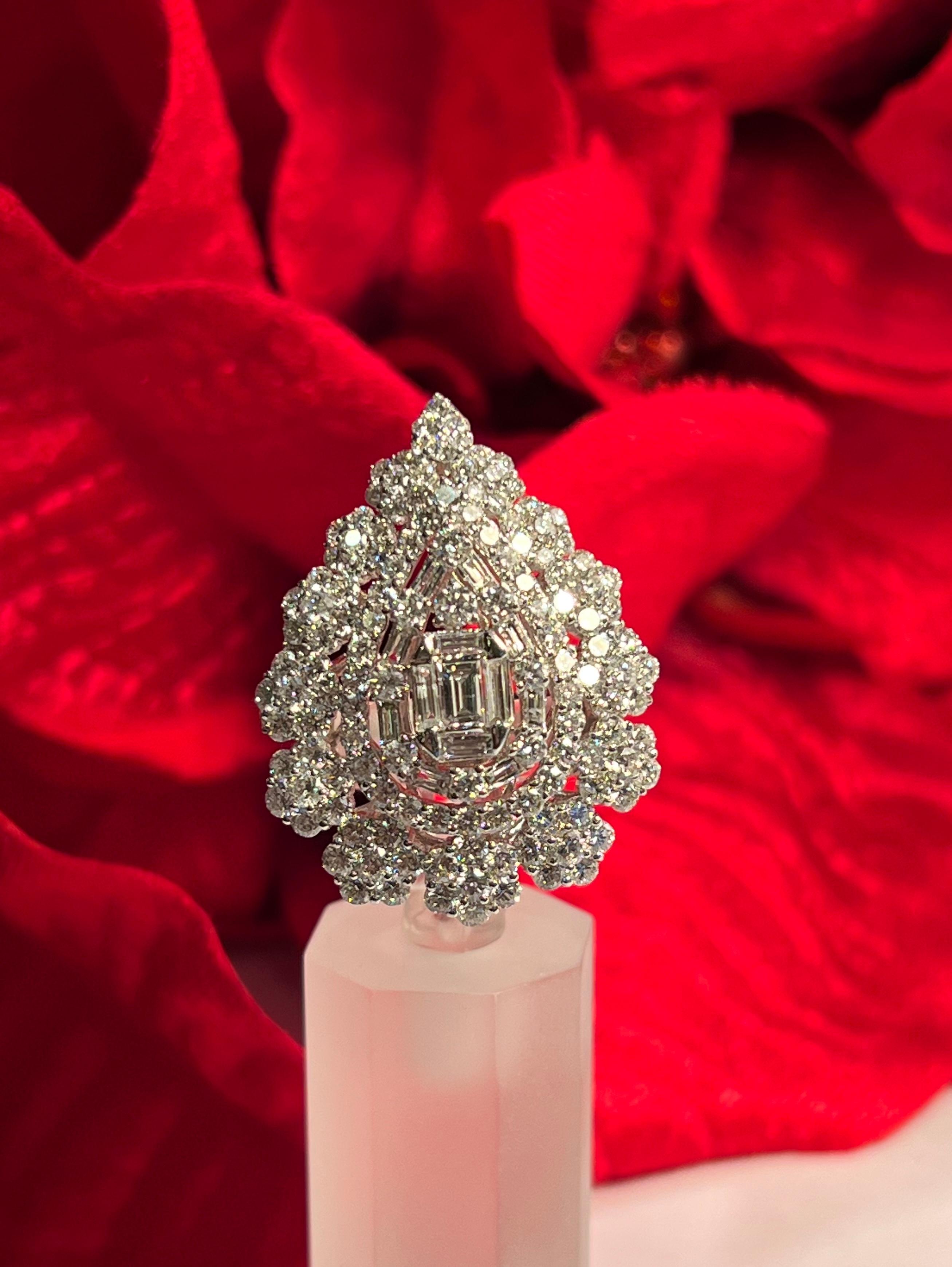 Very exquisite, 18 karat white gold pear shaped diamond cluster cocktail ring features a slightly domed center and an array of baguette diamonds in the middle creating an illusion of a large emerald cut diamond as the focal point in the middle.