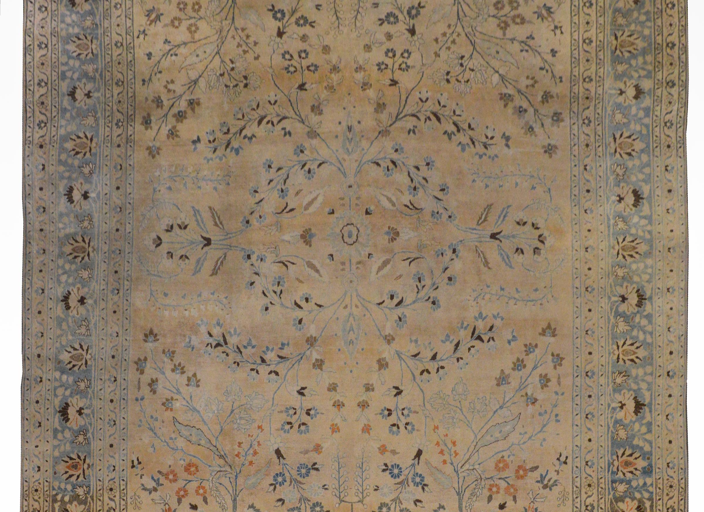 An exquisite early 20th century Persian Tabriz rug with an incredible and striking delicately woven mirrored tree-of-life pattern woven in light and dark indigo, brown, taupe, and orange vegetable dyed wool on a gorgeous champagne colored ground.