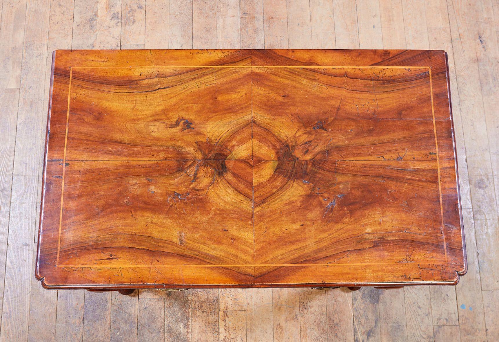 An exquisite early English walnut lowboy of one larger and two smaller drawers, exhibiting fine quality craftsmanship including quarter veneered book matched top with satinwood surround inlay, inlaid drawer fronts, re-entrant corners to top, tulip