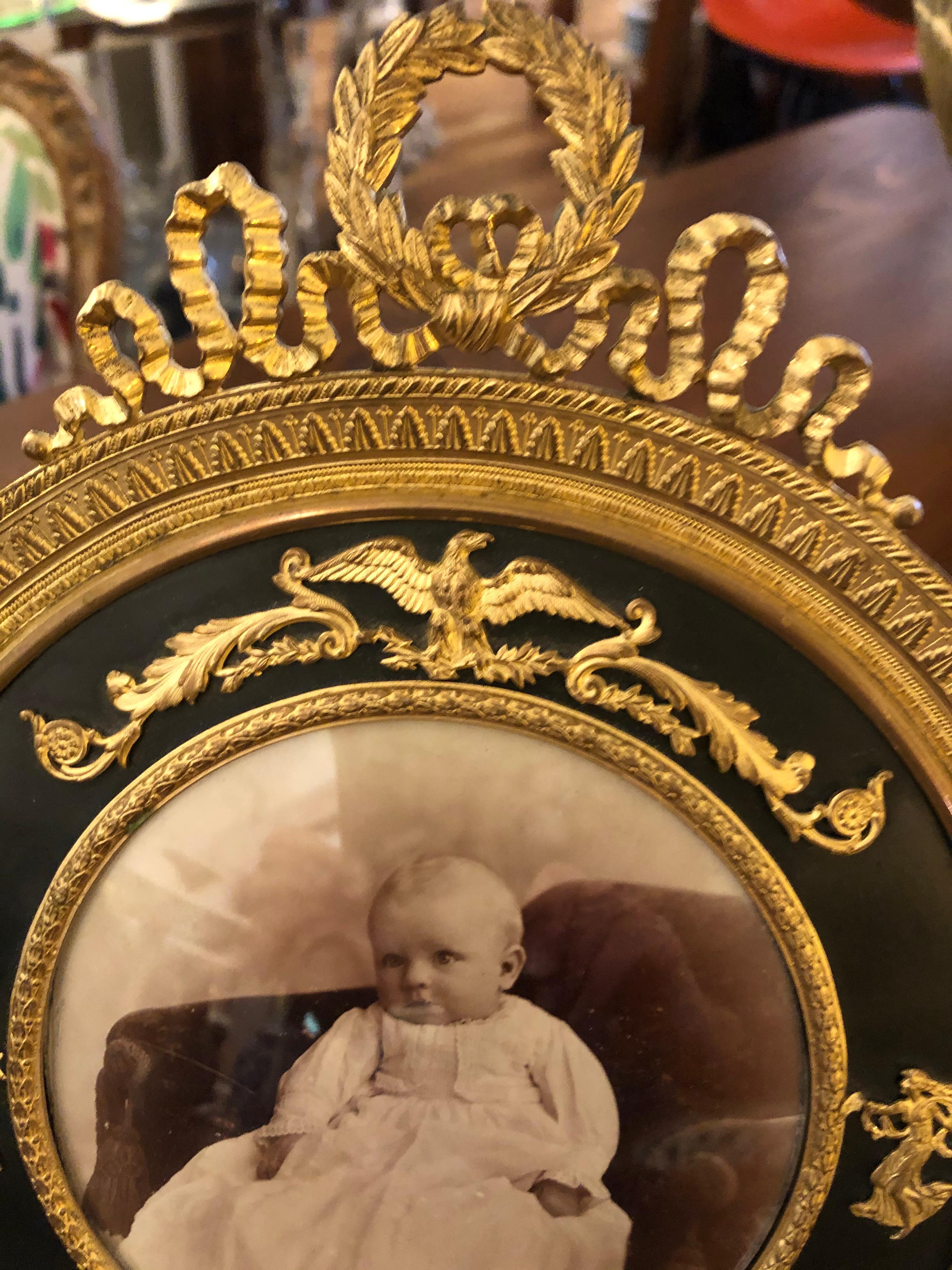 Perhaps the prettiest photo frame ever. French Empire antique gilt and patinated bronze frame having incredible details with maidens, spread eagle, and wreath on the top.