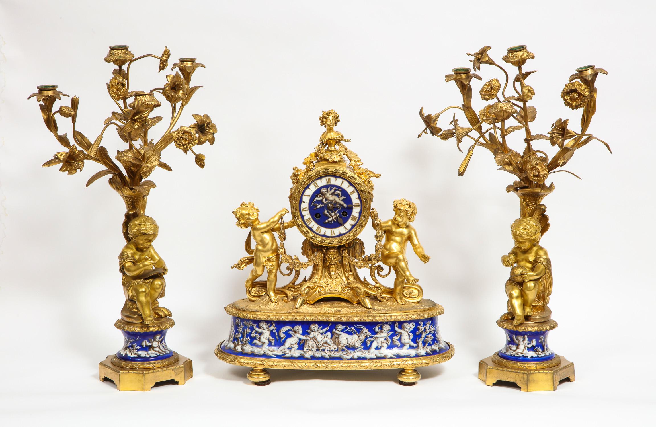 Exquisite French ormolu bronze and blue porcelain mounted three-piece clock garniture set, circa 1880.

Comprising of a clock and pair of candelabra.

The clock's porcelain dial decorated with cupids flanked by spirited putto with floral
