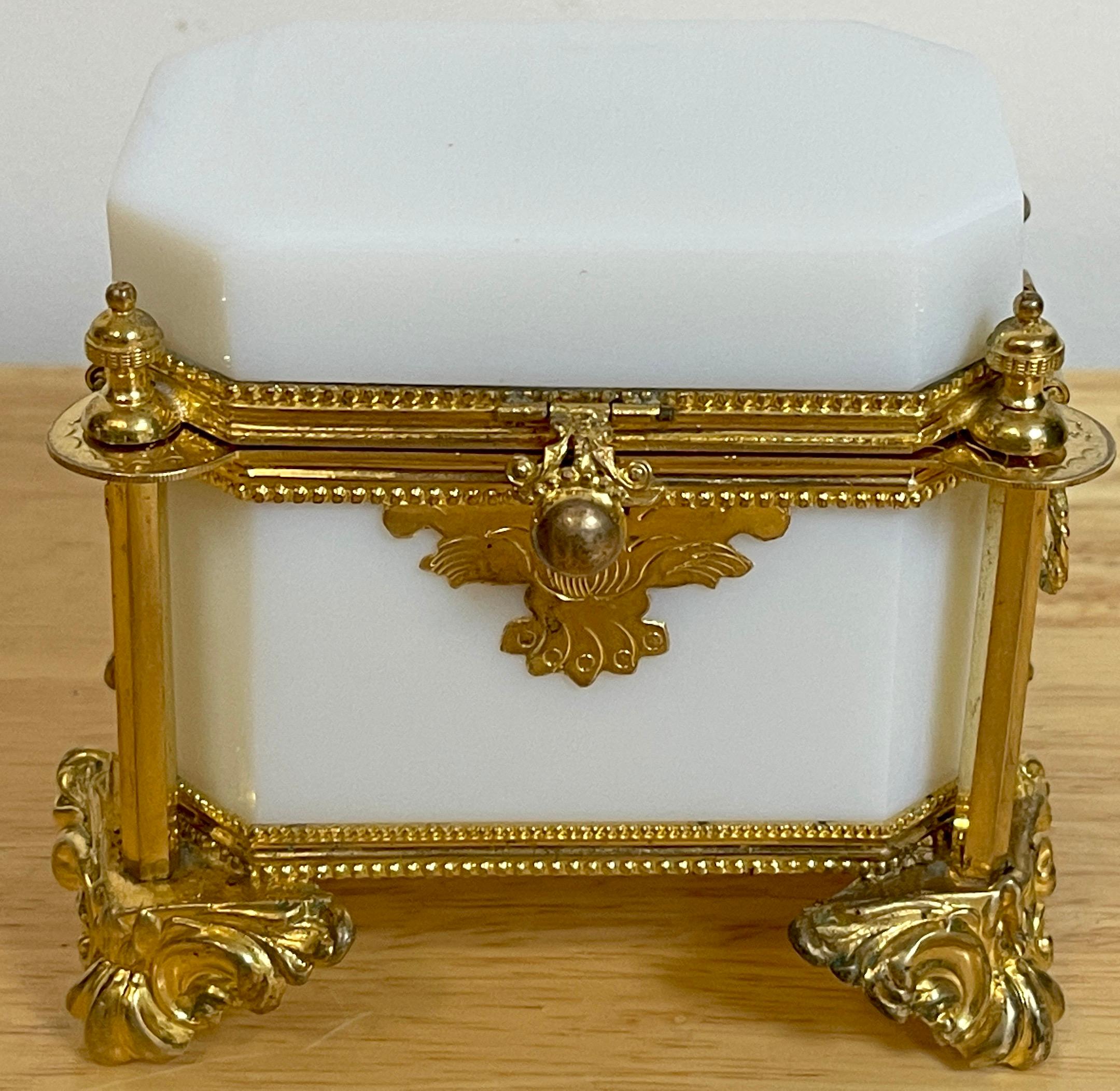 Exquisite French ormolu mounted white Opaline diminutive box, C 1865
Of beveled rectangular from with cross cut corners, flanked by four ormolu urn columns,raised on splay feet. with twin braided oval ring handles. When opened the the interior