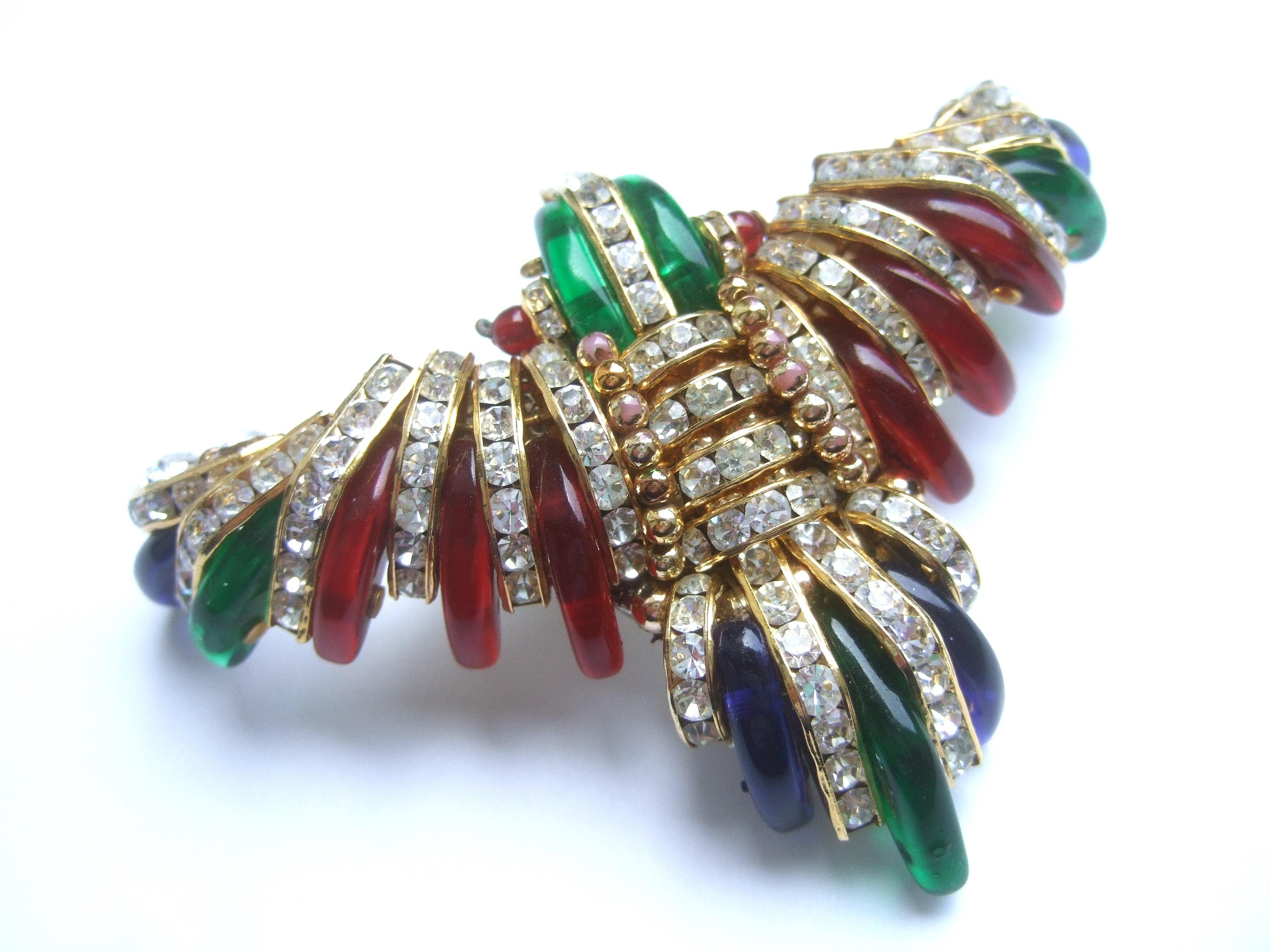Exquisite glass & crystal large bird brooch c 1970s
The large scale stylized bird brooch is embellished with slivers of emerald green,
sapphire blue & ruby red glass color claw shaped settings

Interspersed within the jewel-tone glass settings are