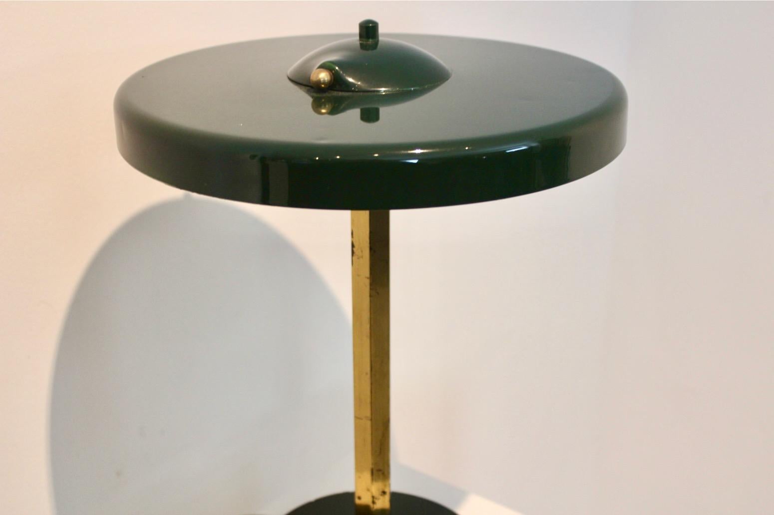 Rare collectable Table lamp found in France with origin 1970s. This sophisticated Mid-Century Table Lamp has a robust brass base on a subtle green steel foot in the same green color as the steel shade. The shade comes with a beautiful asymmetric