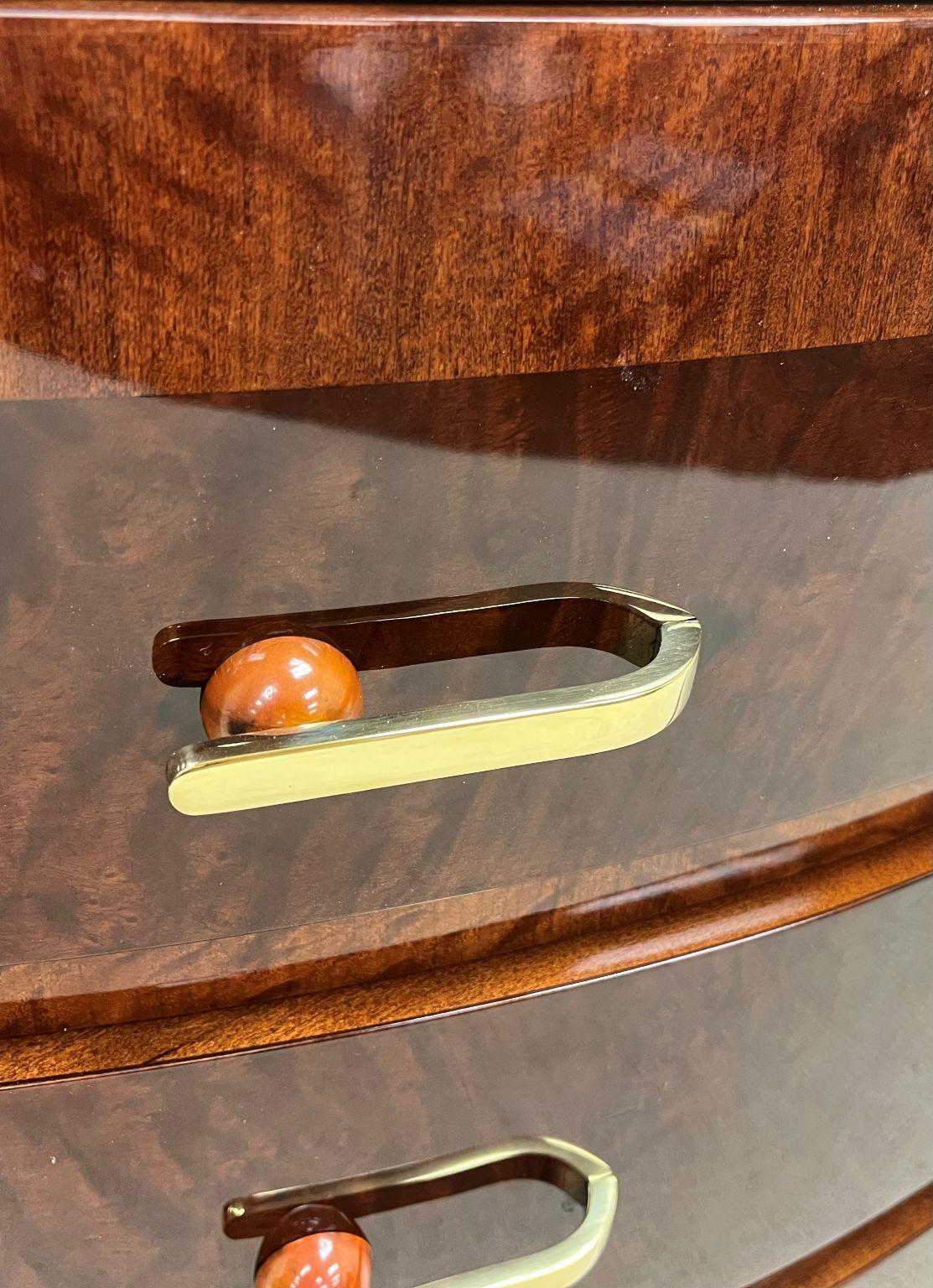 This magnificent rare example of a half circle chest of drawers is from the Redlion Furniture Company Circa American 1930’s. It has spectacular book match Burl veneer with incredible Bakelite and polished Brass hardware. There is a paper label on