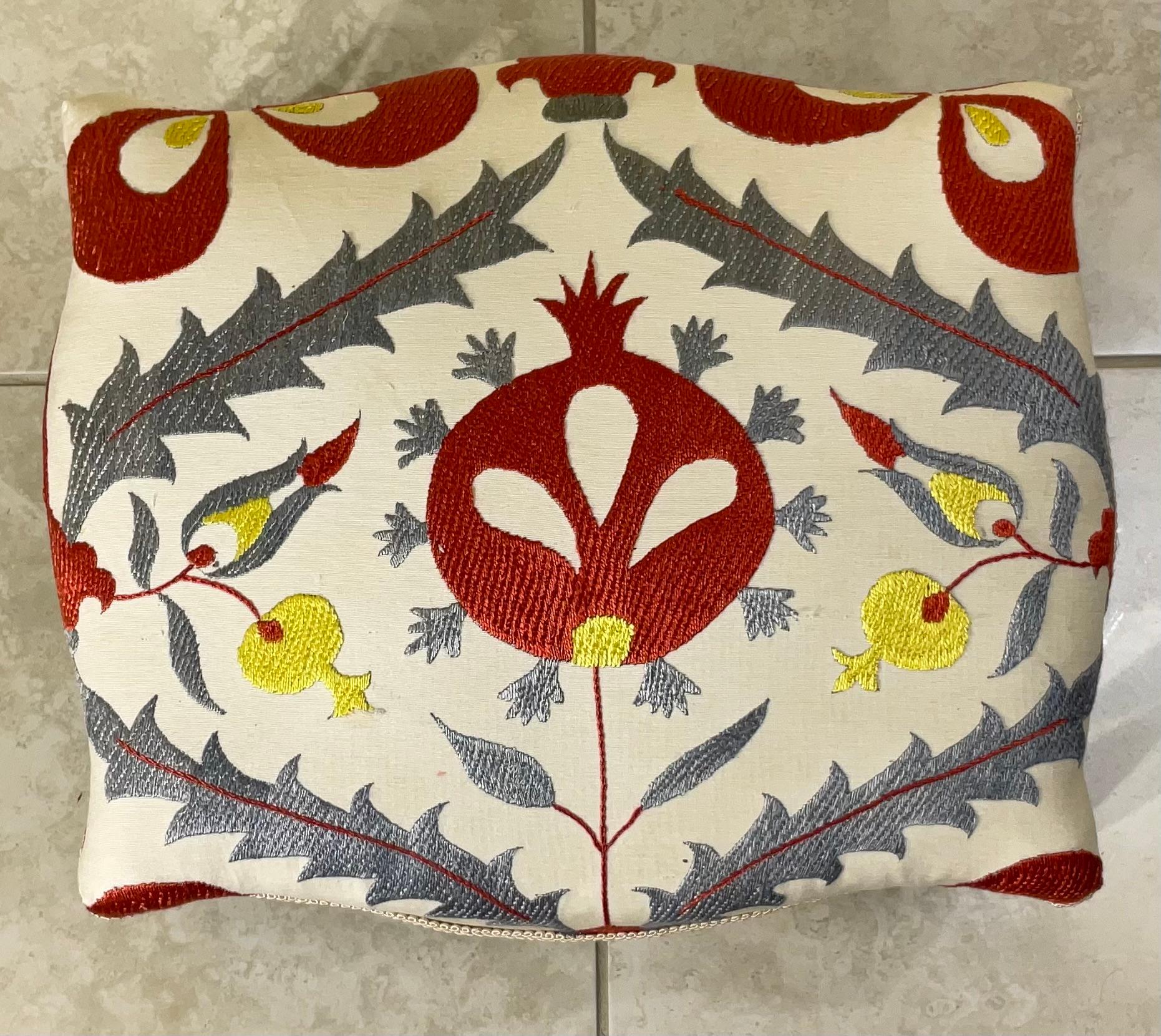 Dieser einzigartige, handbestickte Suzani-Hocker ist ein echter Gesprächsstoff, der traditionelle Kunstfertigkeit mit funktionaler Eleganz verbindet. Dieses bezaubernde Stück ist mehr als nur eine Fußstütze; es ist ein Zeugnis jahrhundertealter