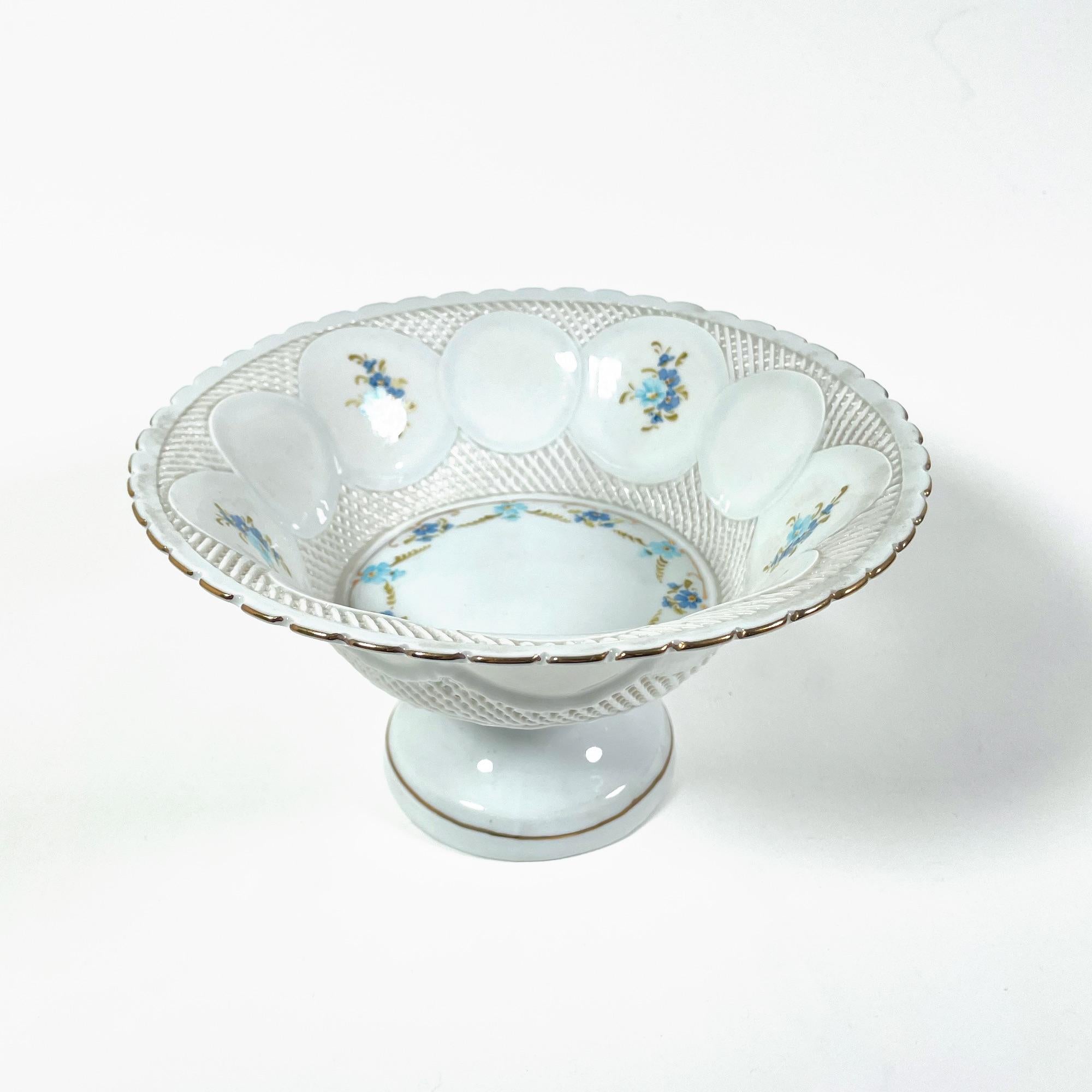 Cette coupe à fruits exquise est un véritable trésor de l'artisanat du XIXe siècle. Fabriquée en porcelaine fine de Limoges, cette pièce présente un magnifique motif peint à la main de délicates fleurs bleues qui ajoute une touche d'élégance à tout