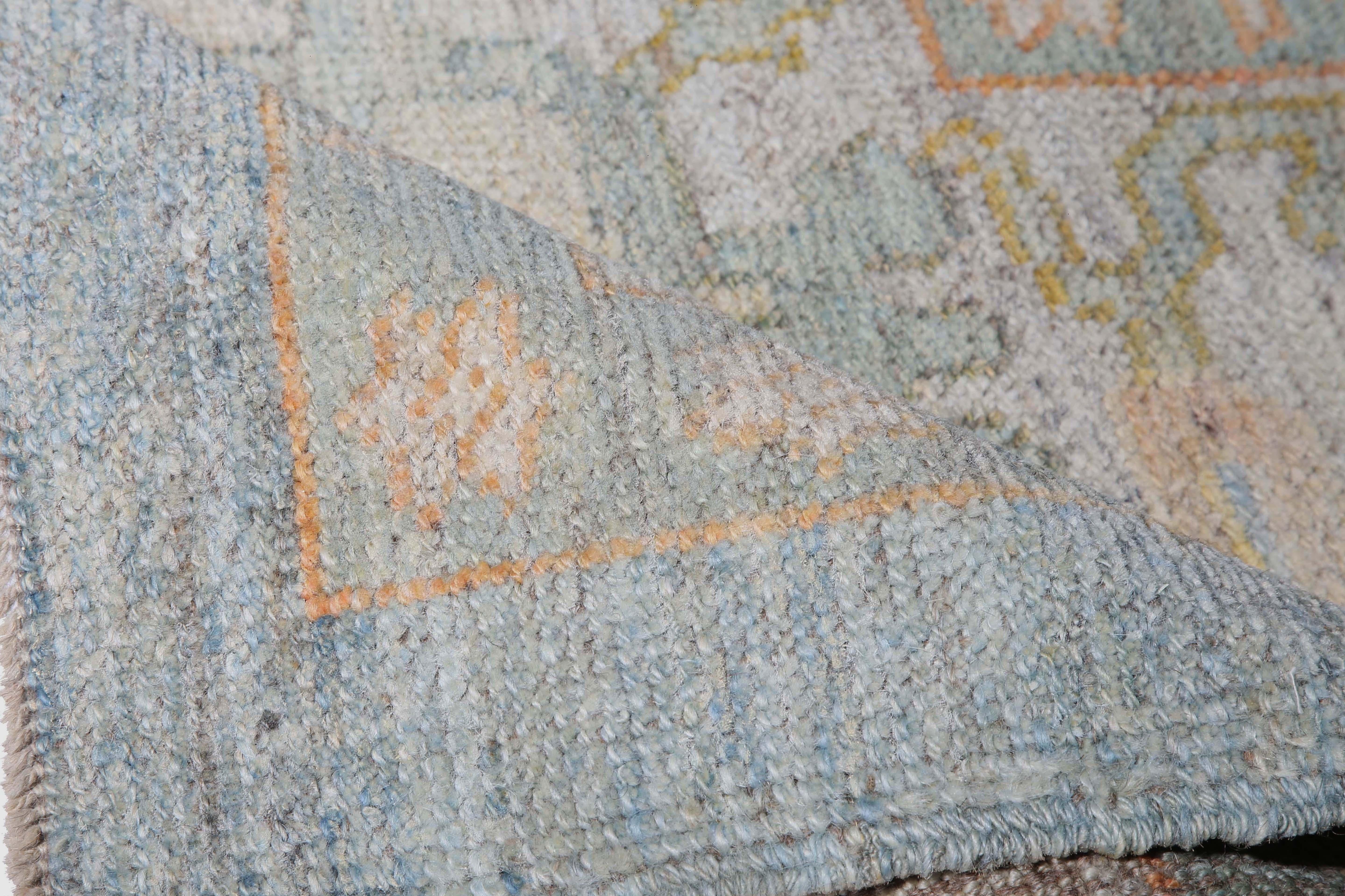 Introducing our exquisite handmade Turkish Oushak rug with a faded look that exudes timeless elegance. This rug boasts a defined border and a light blue background that perfectly complements the light pastel colors used in the design, including