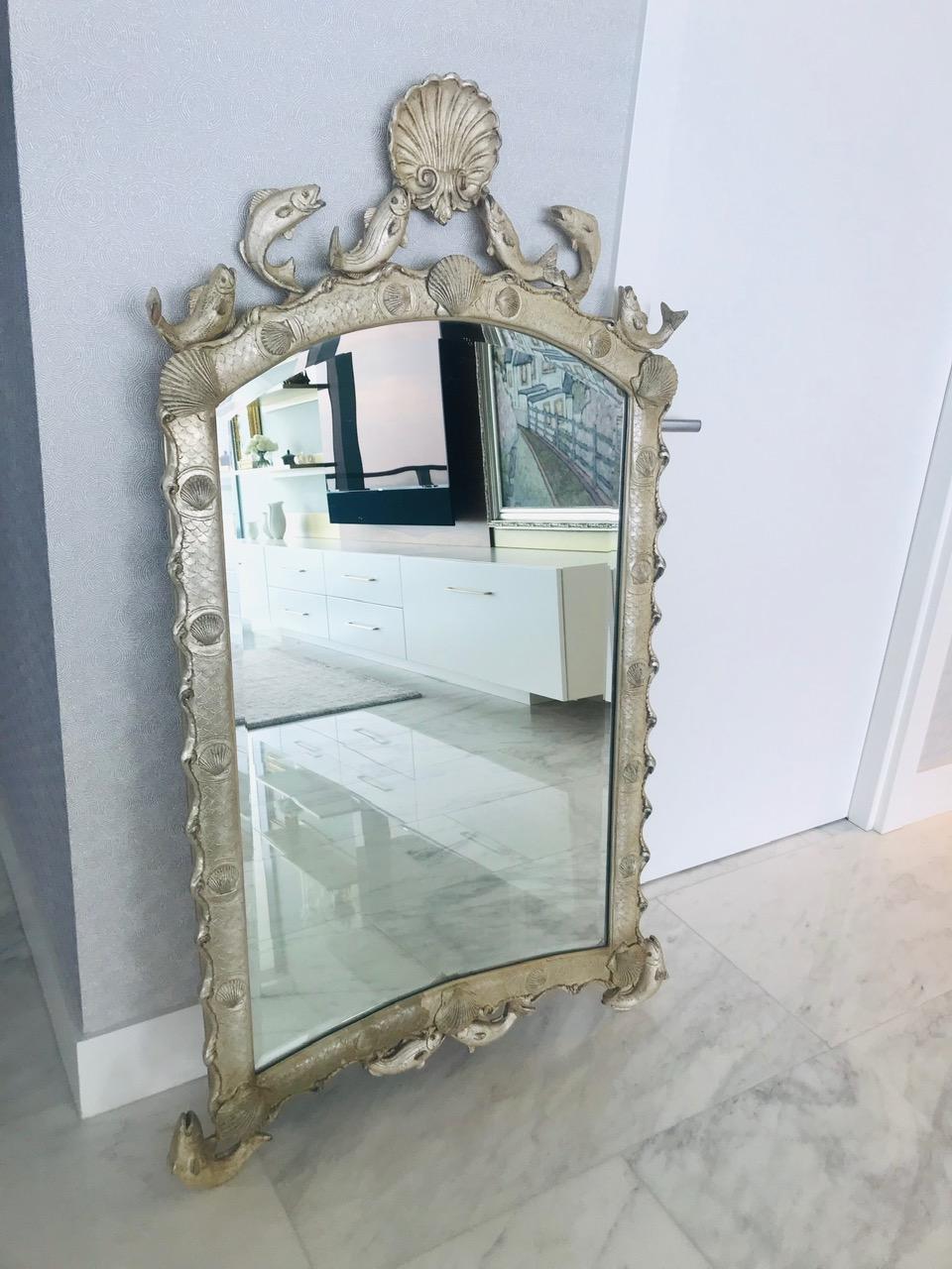 Stunning Venetian style scalloped mirror with ocean sea life theme. The mirror features an arched frame with scalloped borders and with hand laid sterling silver leaf finish. Hand made by artisans using casting technique of wood, resin, and wire to