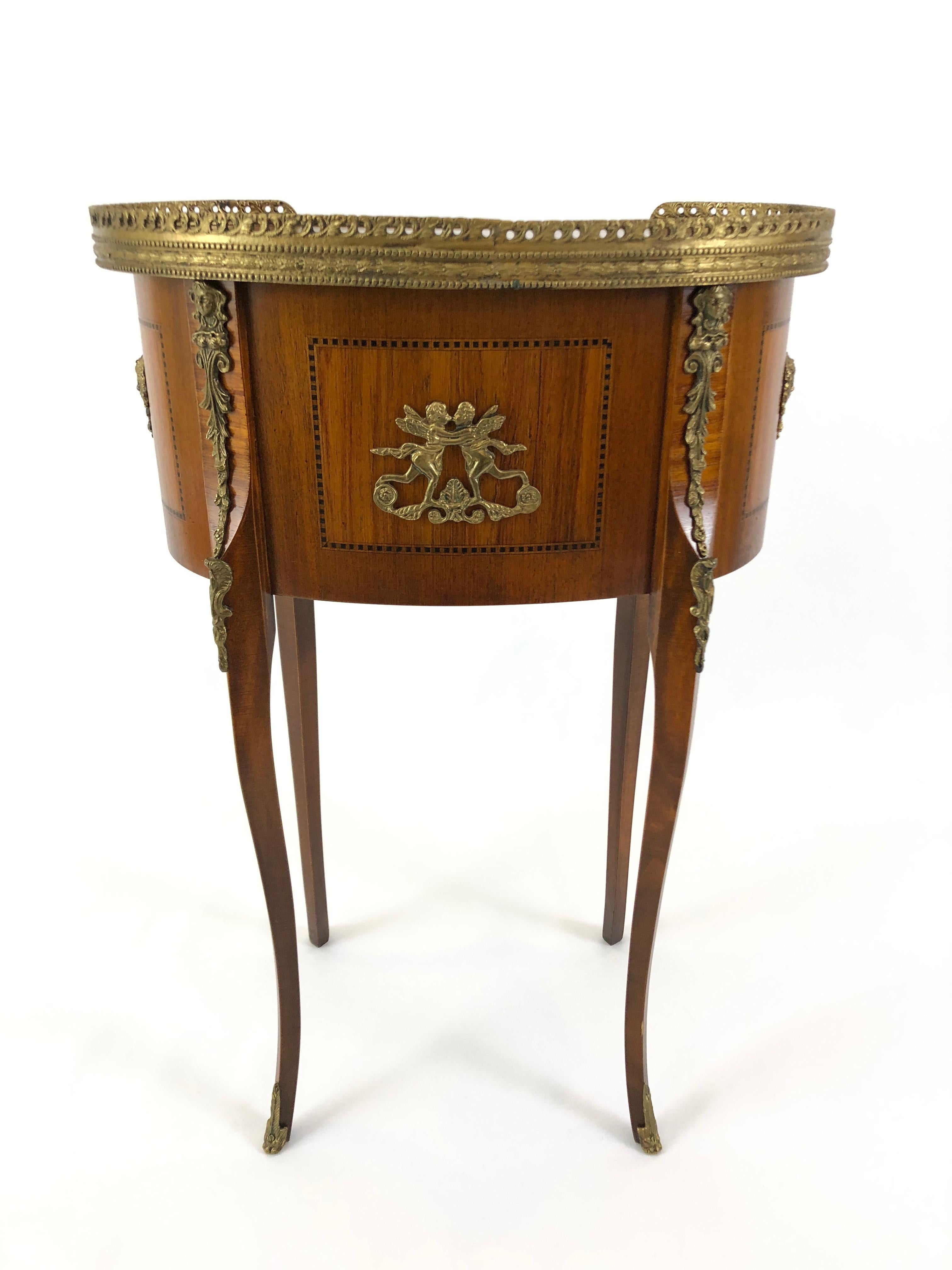 An exquisitely made kidney shaped mahogany side table or nightstand having ebony inlay, two dovetailed drawers, handsome brass gallery and hardware including putti embellishments and caps on the feet. Legs are elegantly thin and curved. Gorgeous